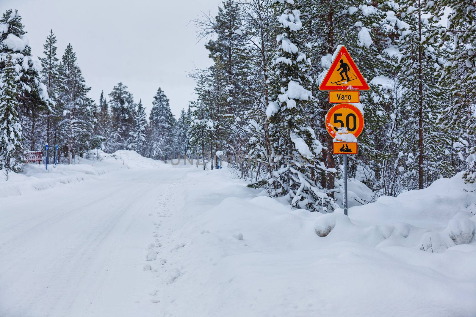 Warning traffic sign, warning skier and snowmobile sign on snowy arctic winter forest.