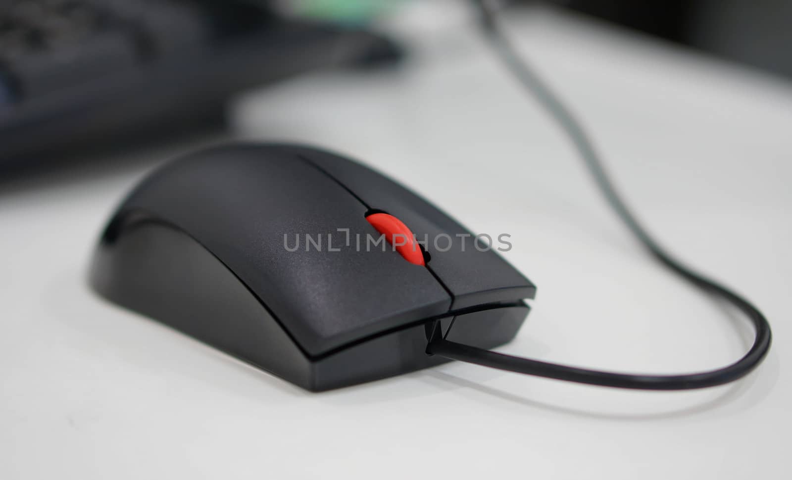 Computer mouse has a black wire attached to the PC, scrolling button is red in the middle.                               