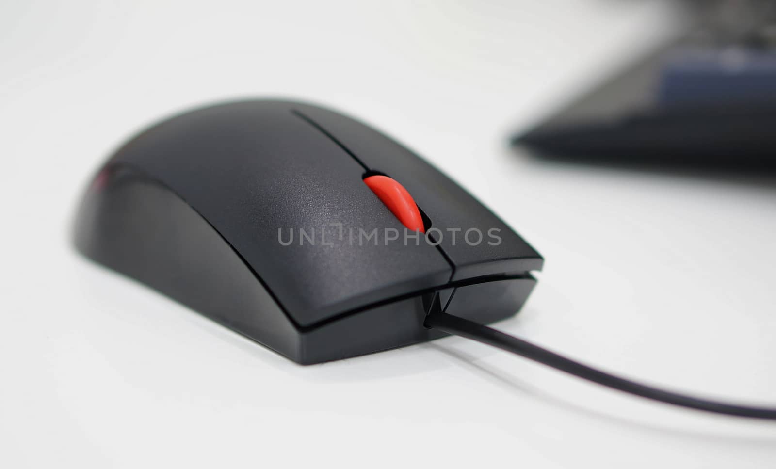 Computer mouse has a black wire attached to the PC, scrolling button is red in the middle.                              