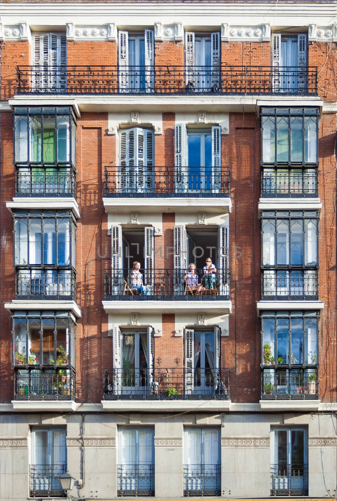 Madrid, Spain - May 6, 2012: Young girls on balconies of a typical building facade on a street of Madrid, Spain