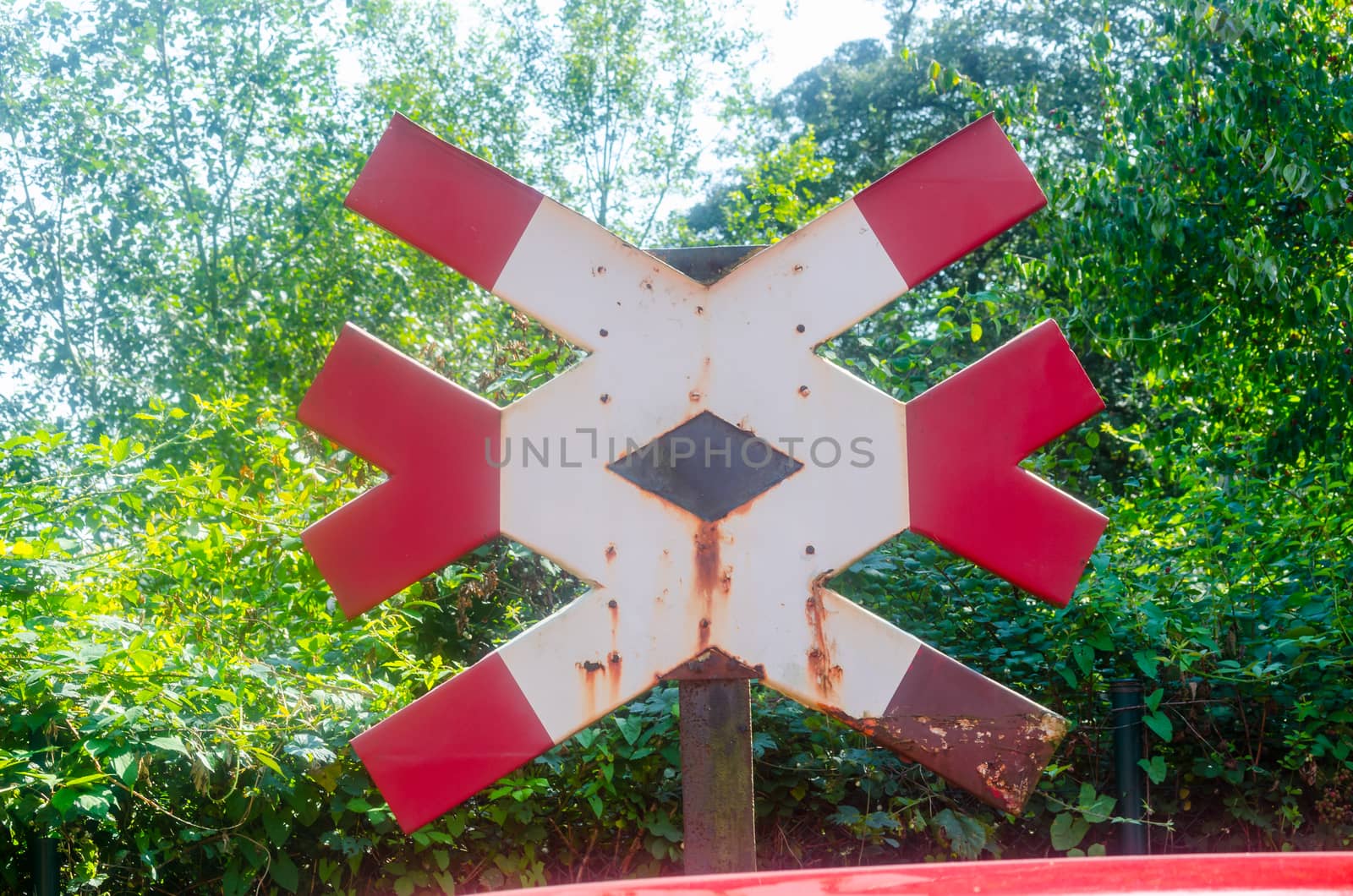 Red White railway signal against a green background.