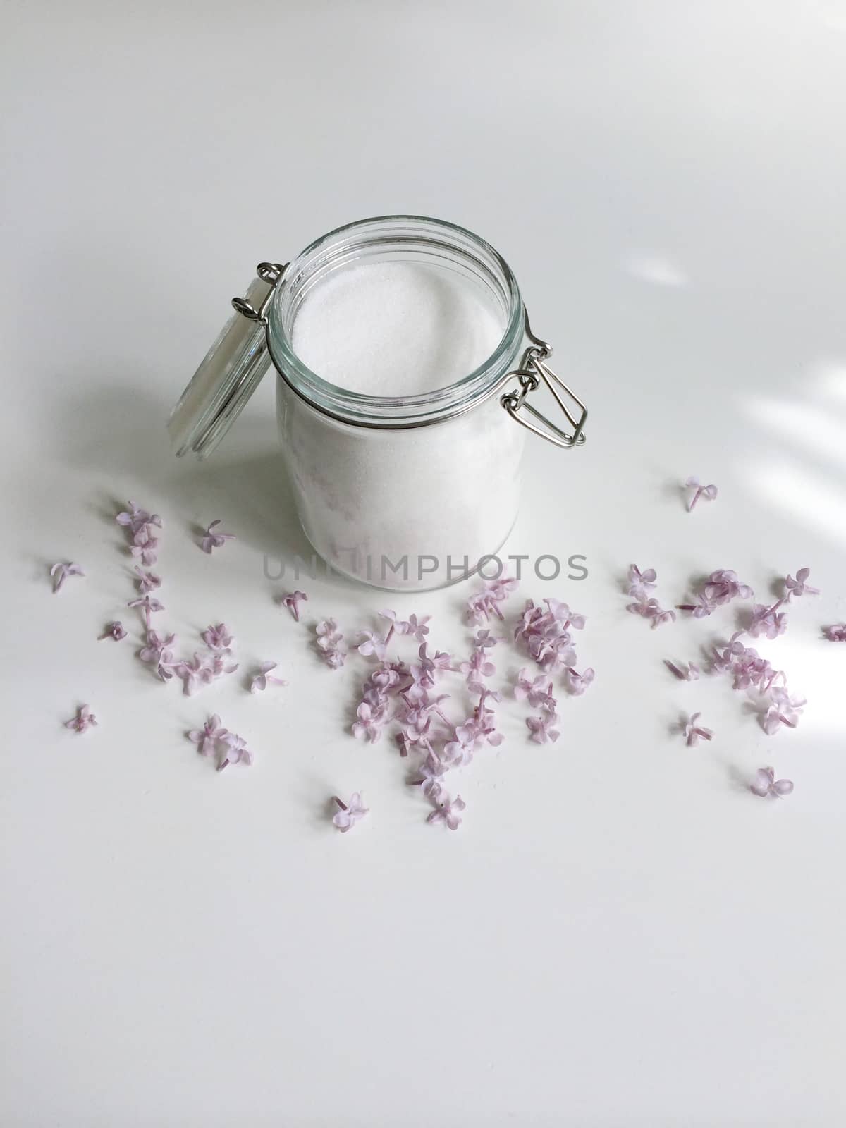 Glass jar of granulated white sugar and lilac flowers