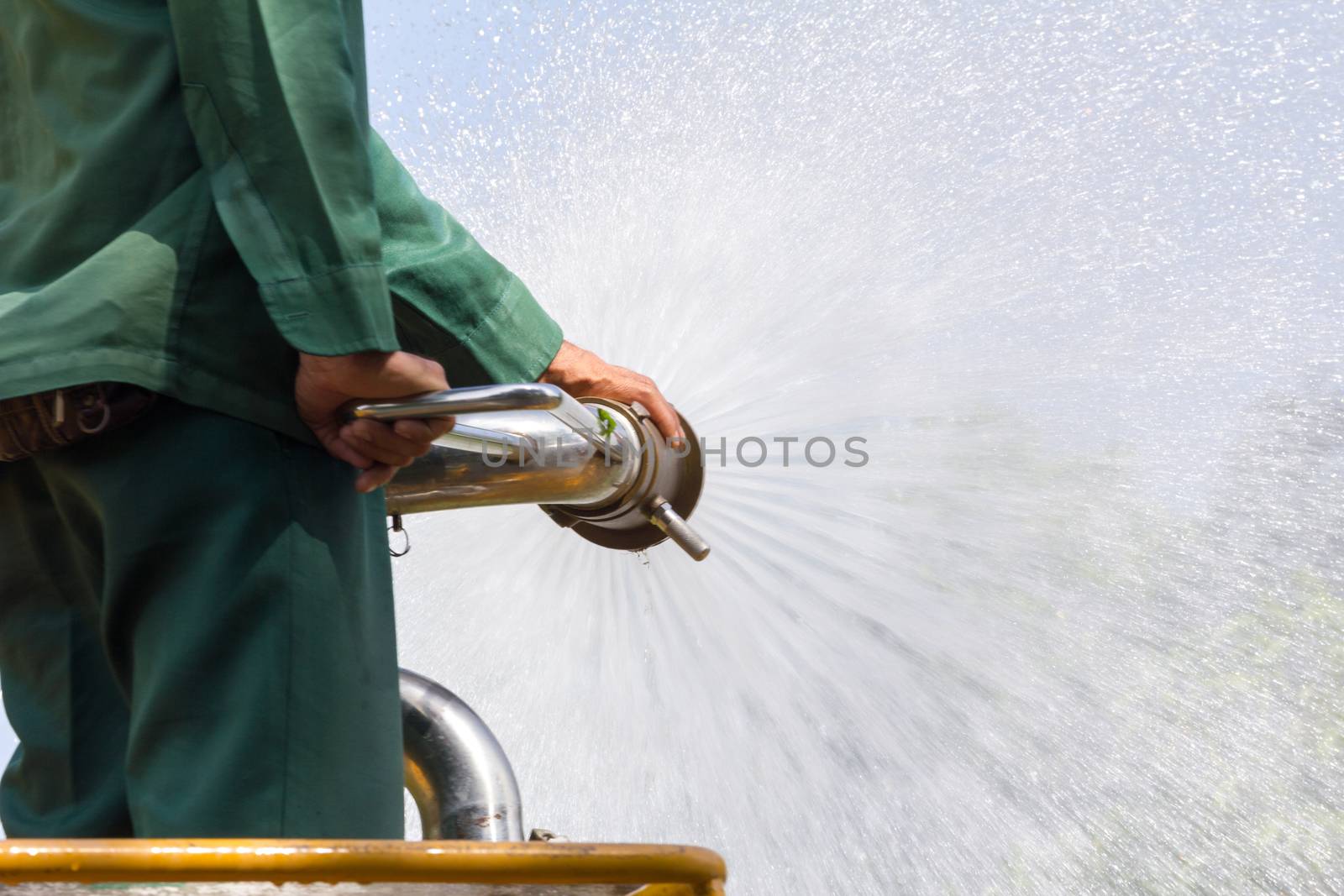 man watering plants on water truck in the park, closeup
