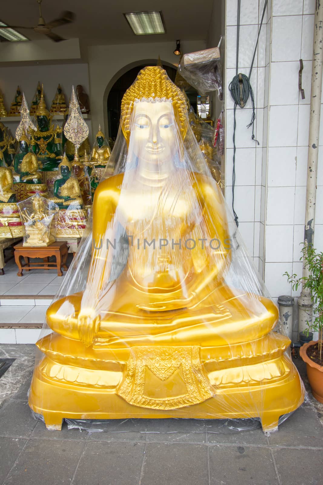 buddha wrapped in plastic for sale in front of the shop