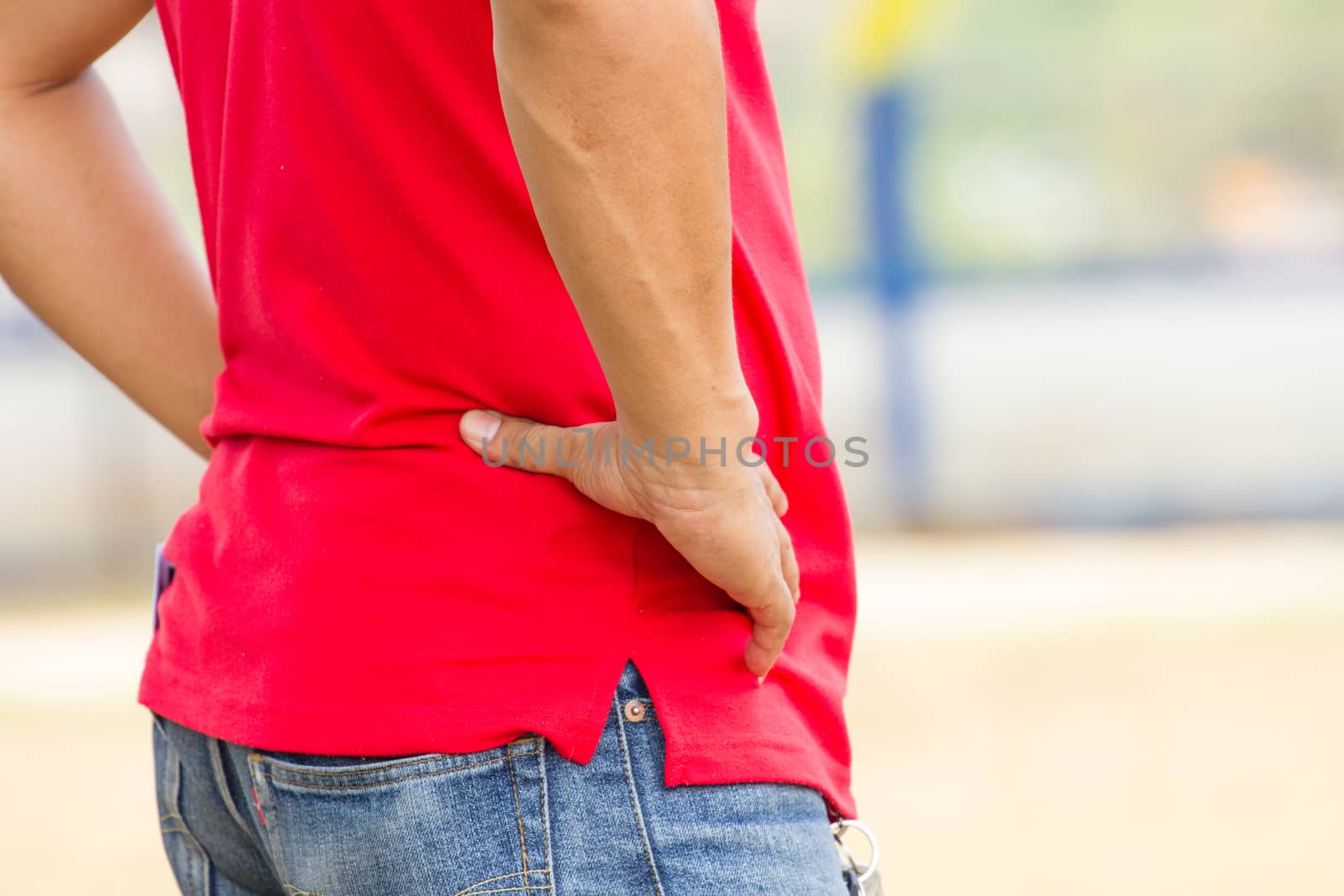 man in red shirt with his hands akimbo on his hips standing by the footballfield, close-up