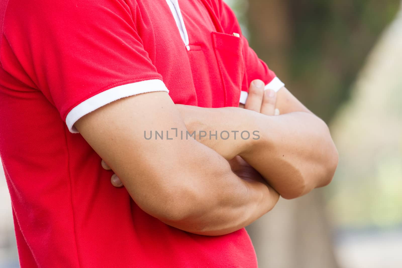 man with arms crossed in a garden.