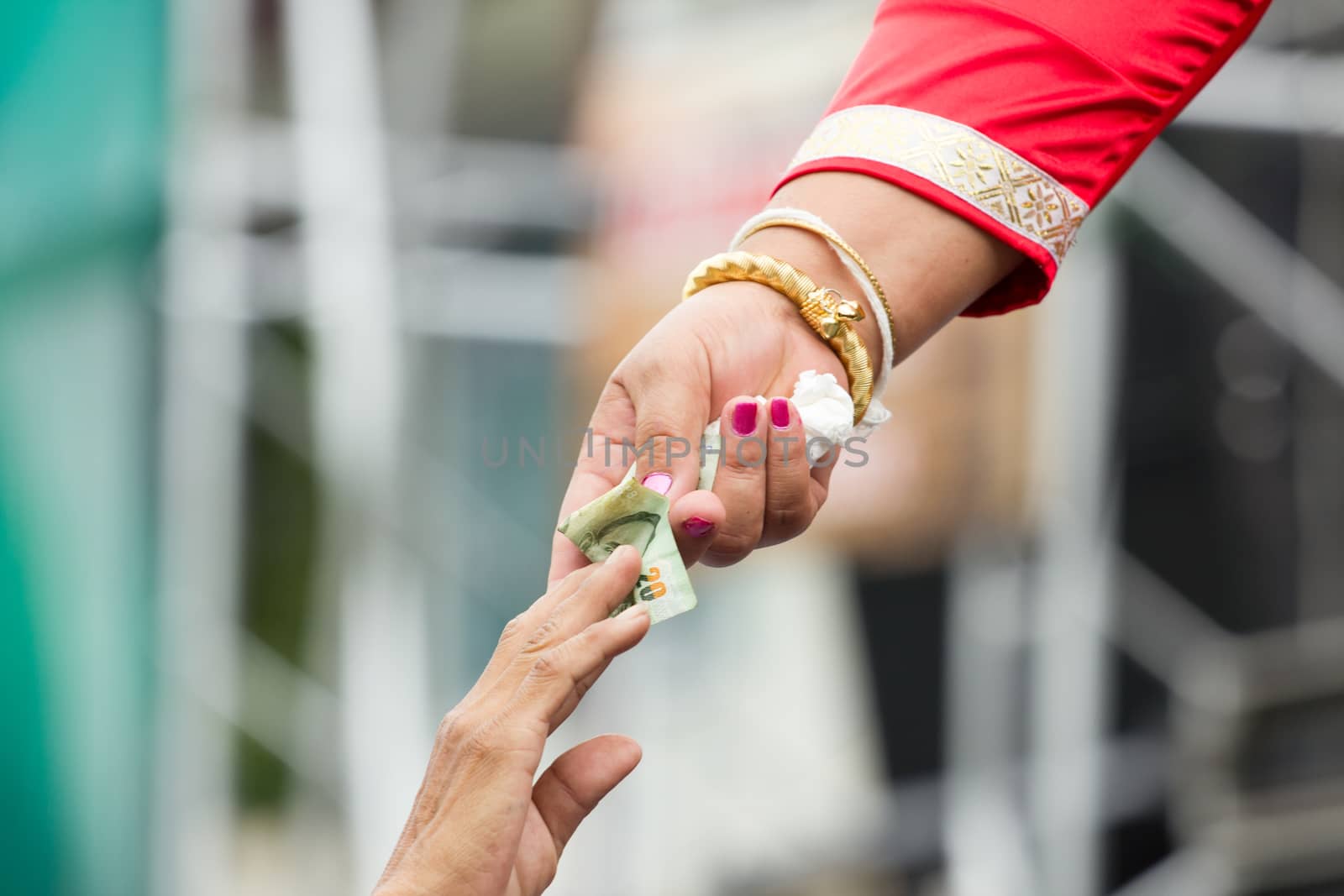 rich woman with gold bracelet giving money to a man.