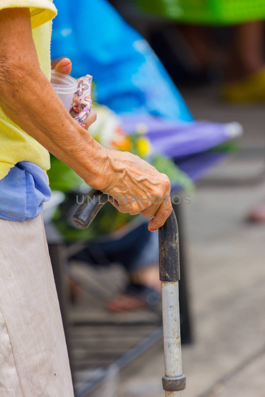 Old woman hand leans on walking stick, close-up