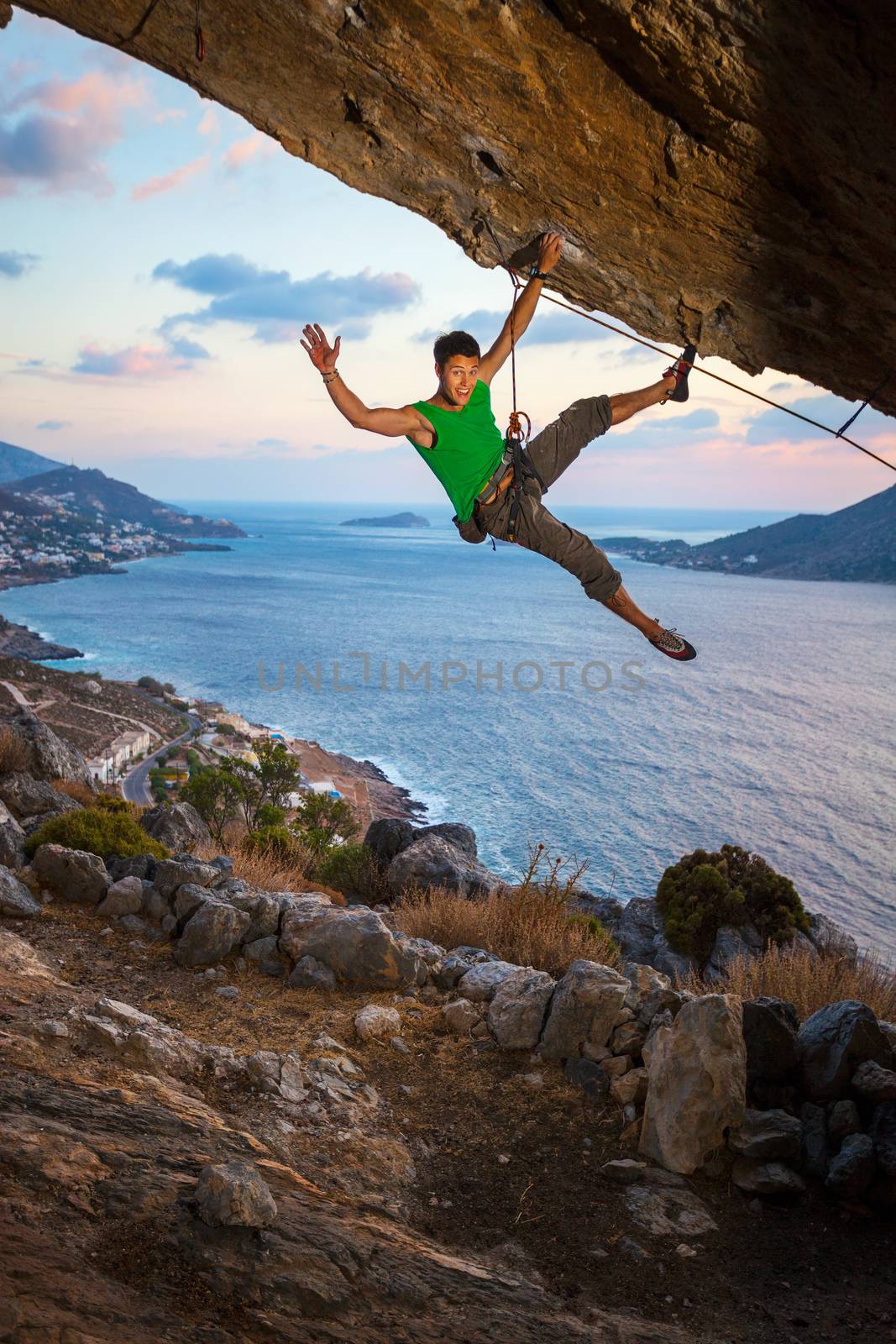 Rock climber waving his hand while climbing by photobac