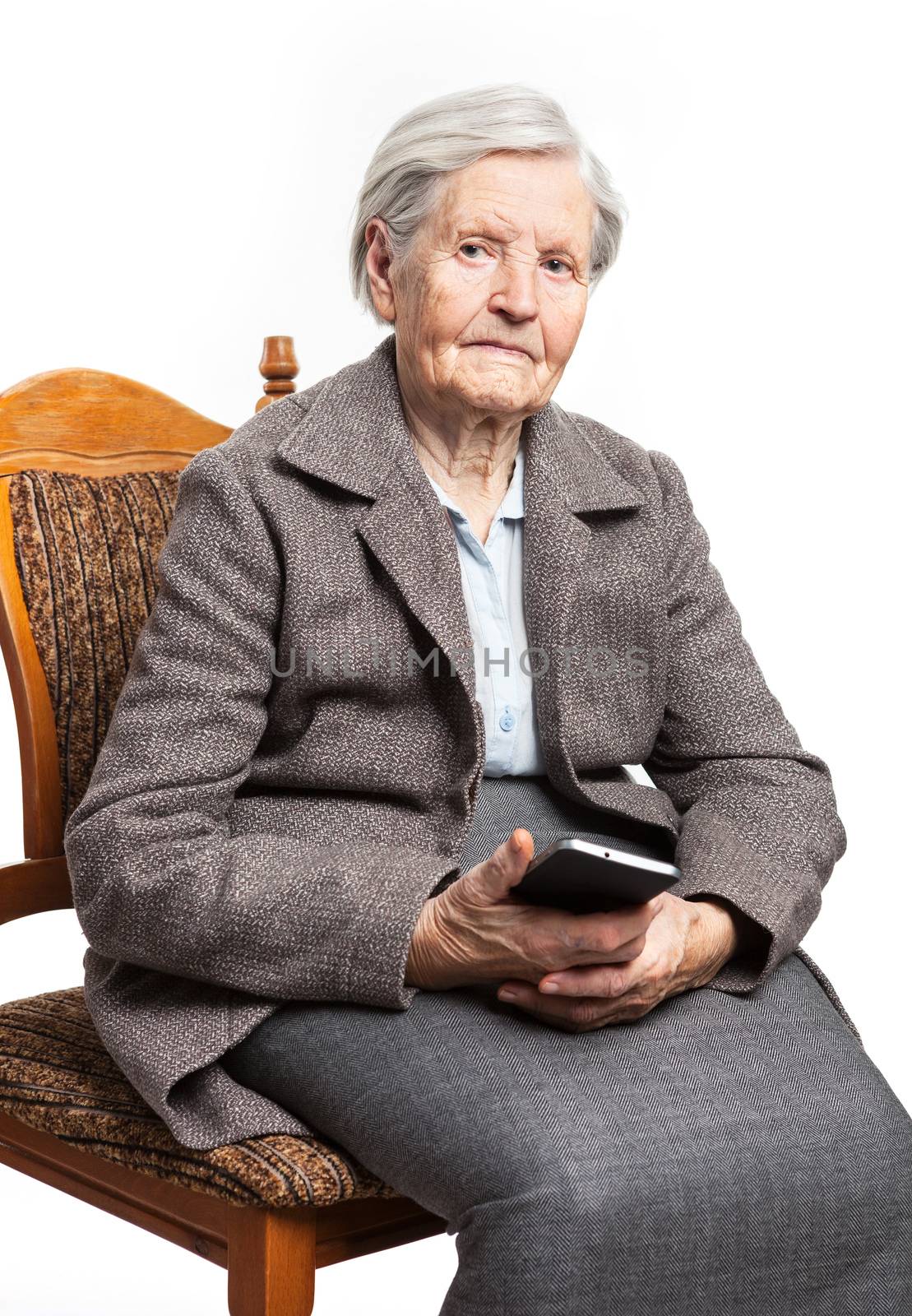 Senior woman sitting on chair and holding phone by photobac