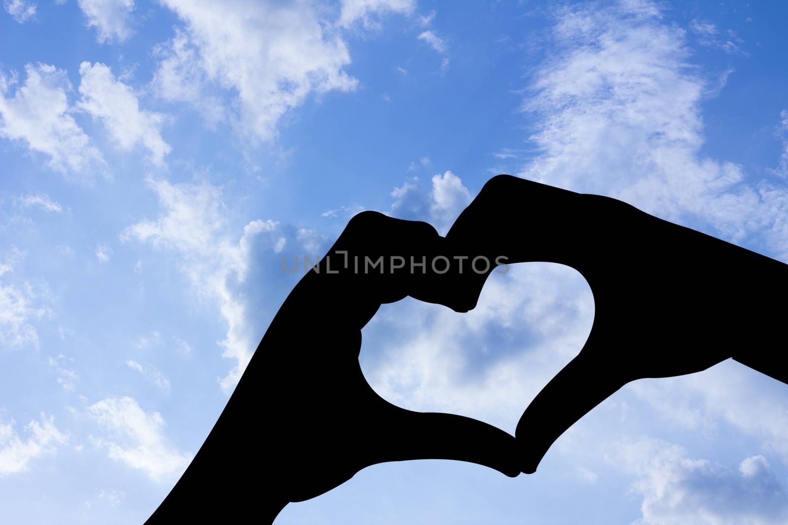 love shape hand silhouette in blue sky.
