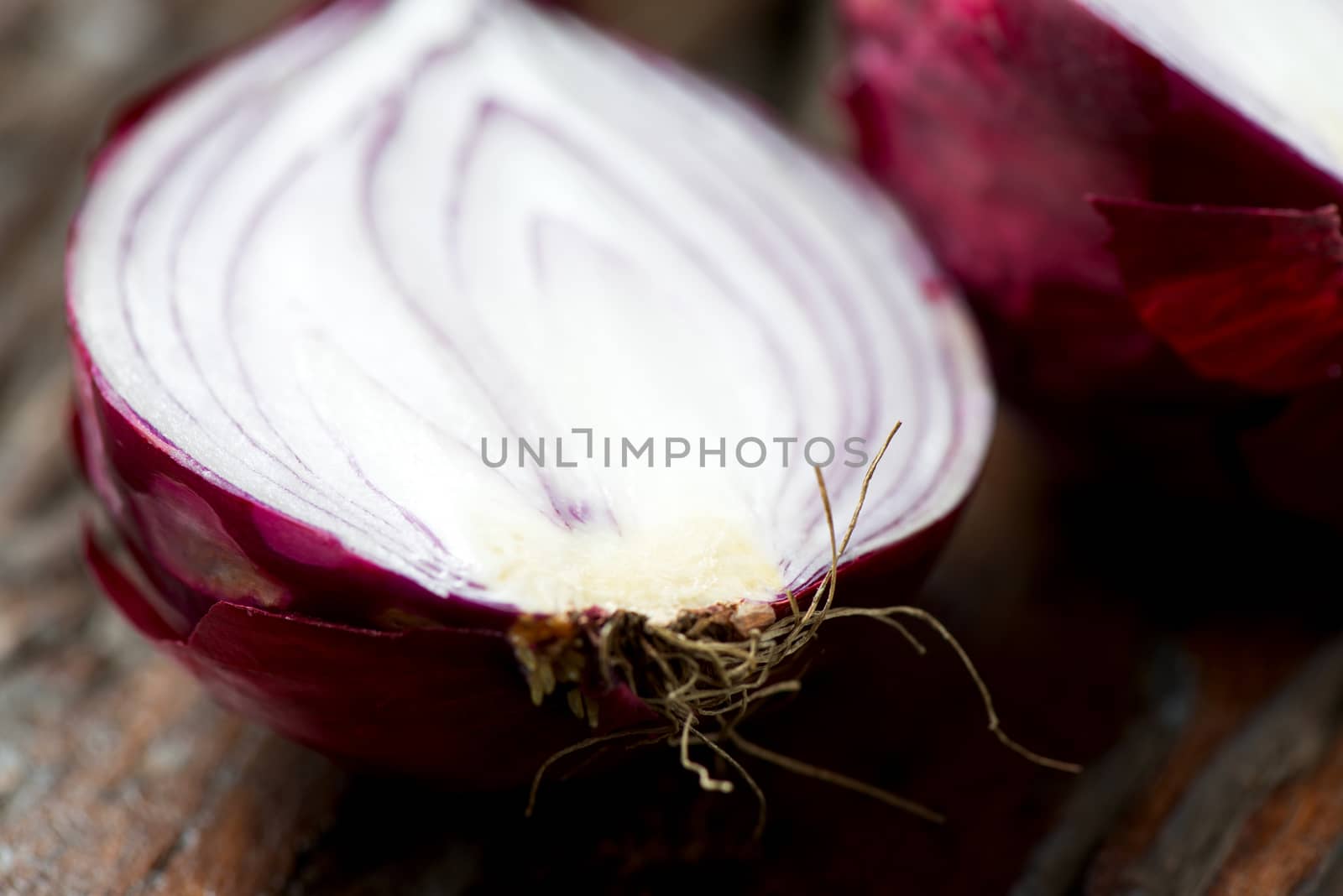 Fresh red onion cut on an old wooden table close up by Nanisimova