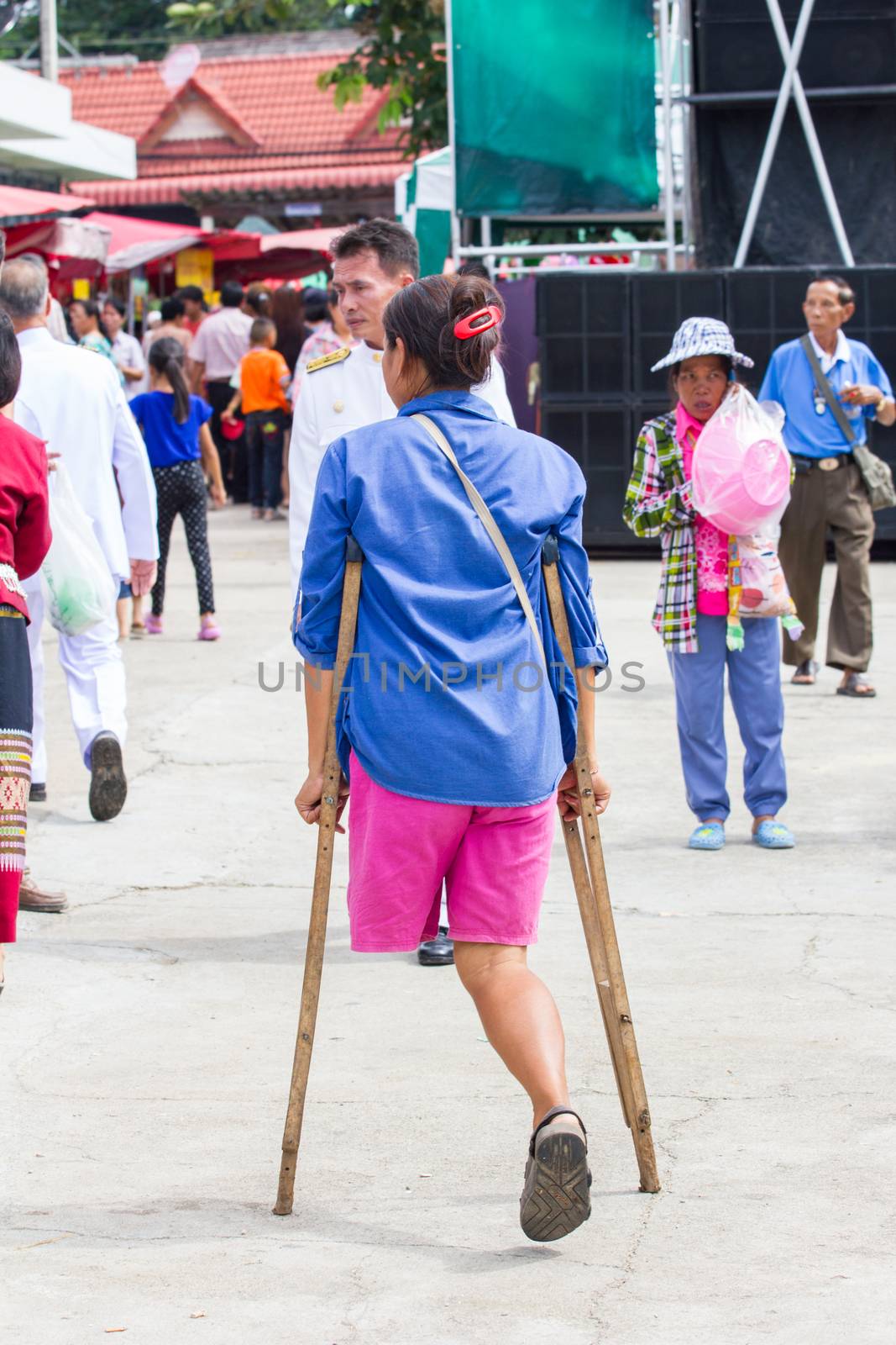 CHIANGRAI, THAILAND - AUG 12: unidentified young disable woman waking in the crowd with crutches on August 12, 2014 in Chiangrai, Thailand.
