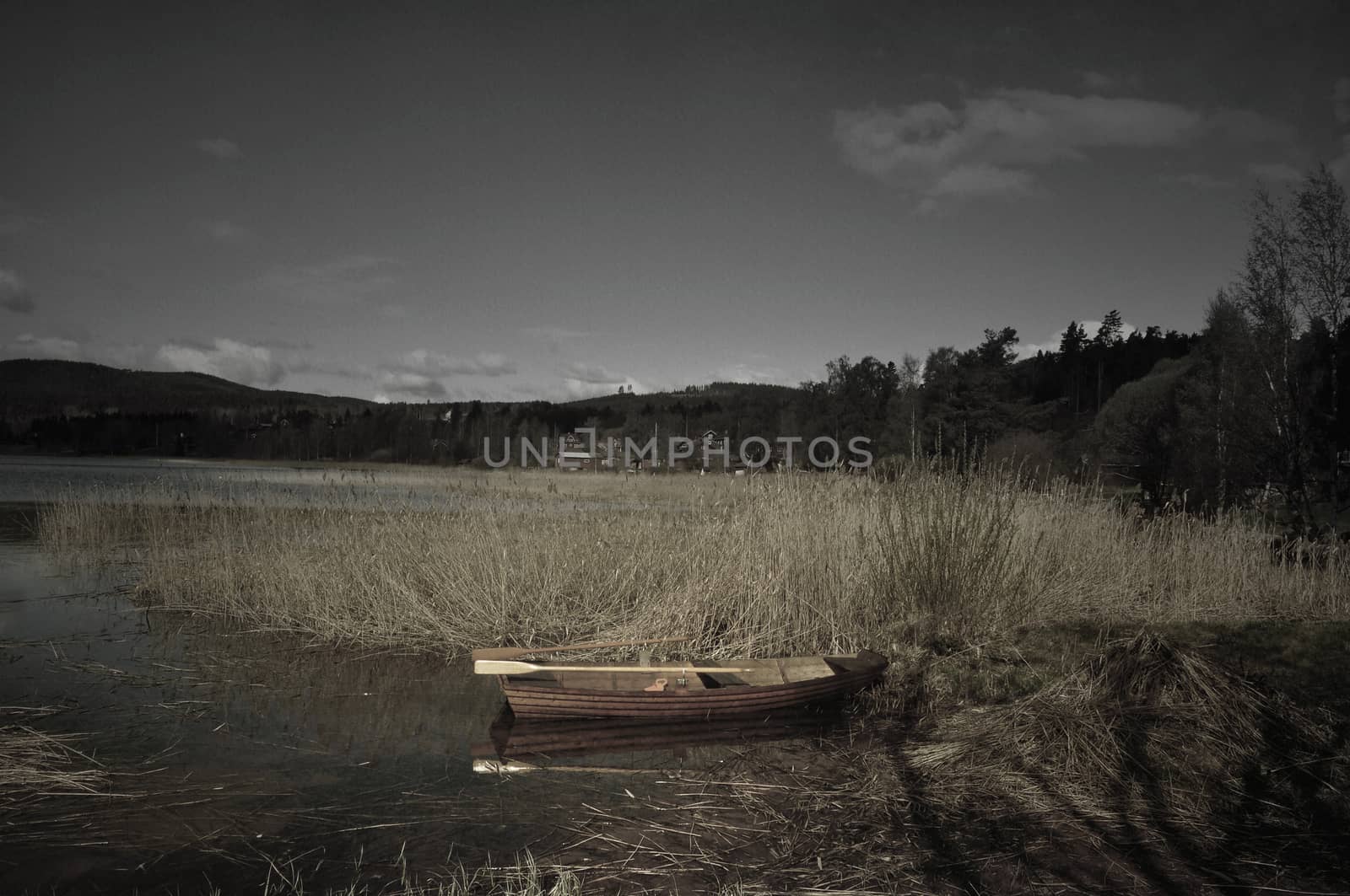 Softly textured image of rowboat on a lake a calm morning in sparse colors.