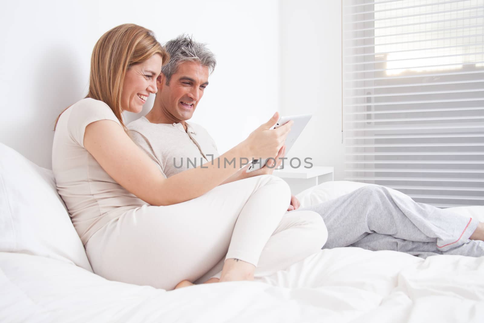 25-30, adult, apartment, attractive, bed, bedroom, caucasian, Couple, fun, handsome, happy, home, horizontal, house, leisure, lifestyle, love, marriage, men, model, nightwear, old, pc, people, person, property, releases, sitting, smile, tablet, two, women, years, young