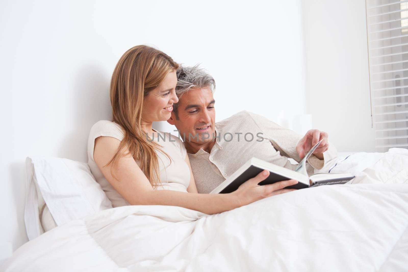 25-30, adult, apartment, attractive, bed, bedroom, book, caucasian, Couple, fun, handsome, happy, home, horizontal, house, leisure, lifestyle, love, marriage, men, model, nightwear, old, people, person, property, reading, releases, sitting, smile, two, women, years, young