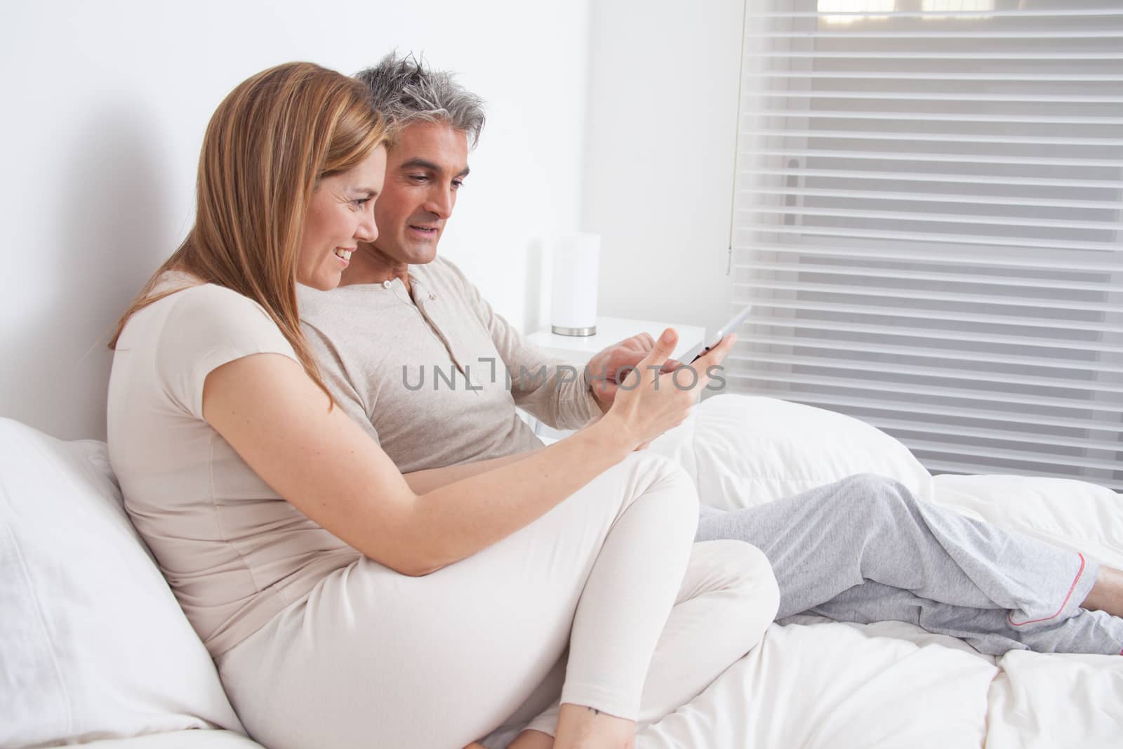 25-30, adult, apartment, attractive, bed, bedroom, caucasian, Couple, fun, handsome, happy, home, horizontal, house, leisure, lifestyle, love, marriage, men, model, nightwear, old, pc, people, person, property, releases, sitting, smile, tablet, two, women, years, young