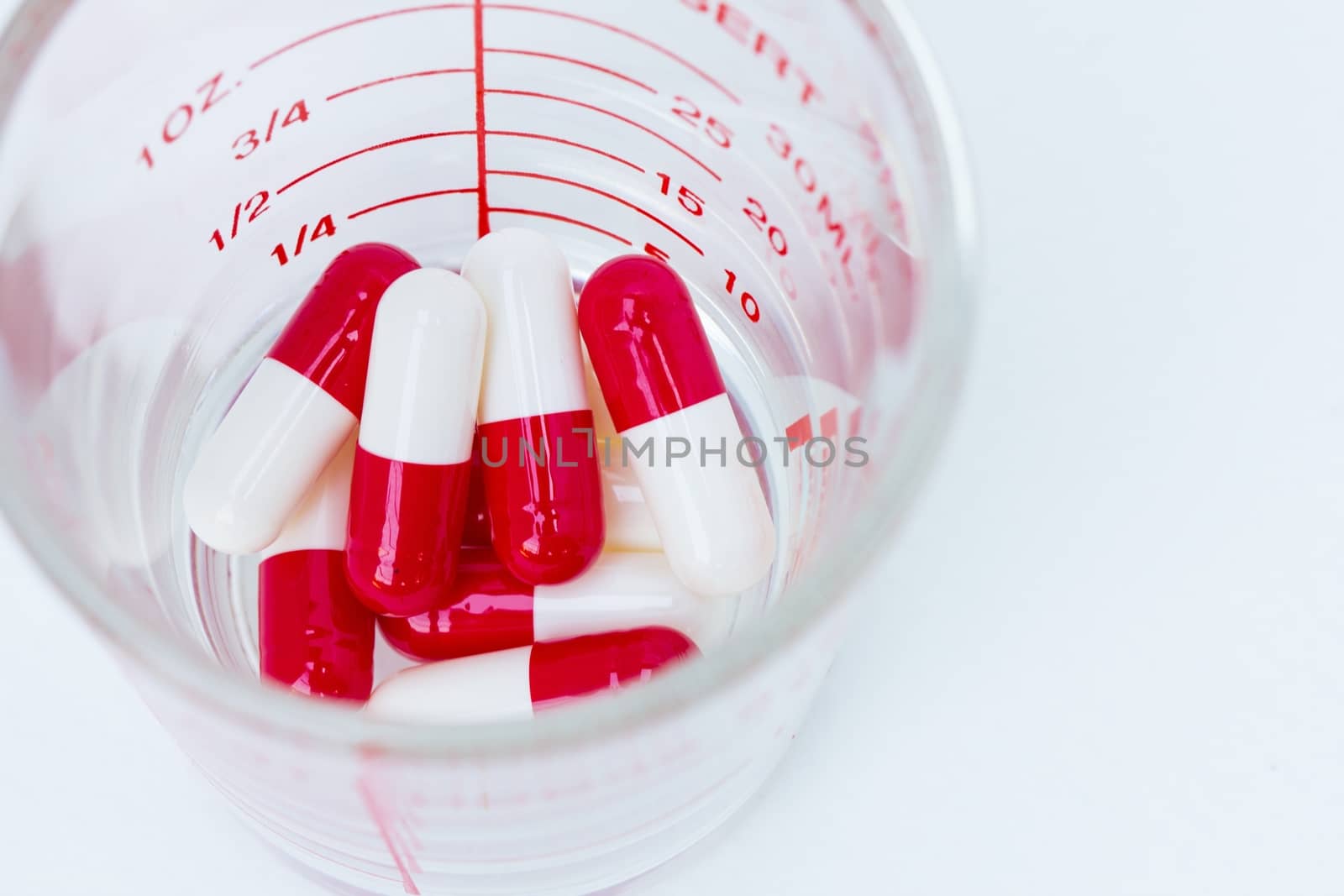 white red capsules  in a cup of glass, shallow depth of field, focusing on capsules