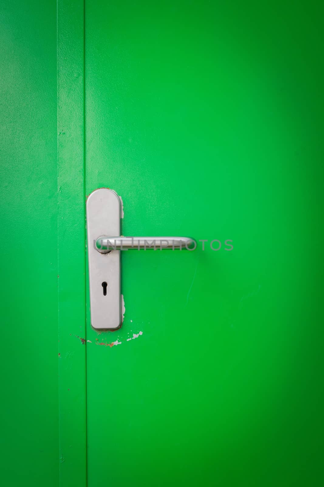 Metal door handle on green steel door, with keyhole