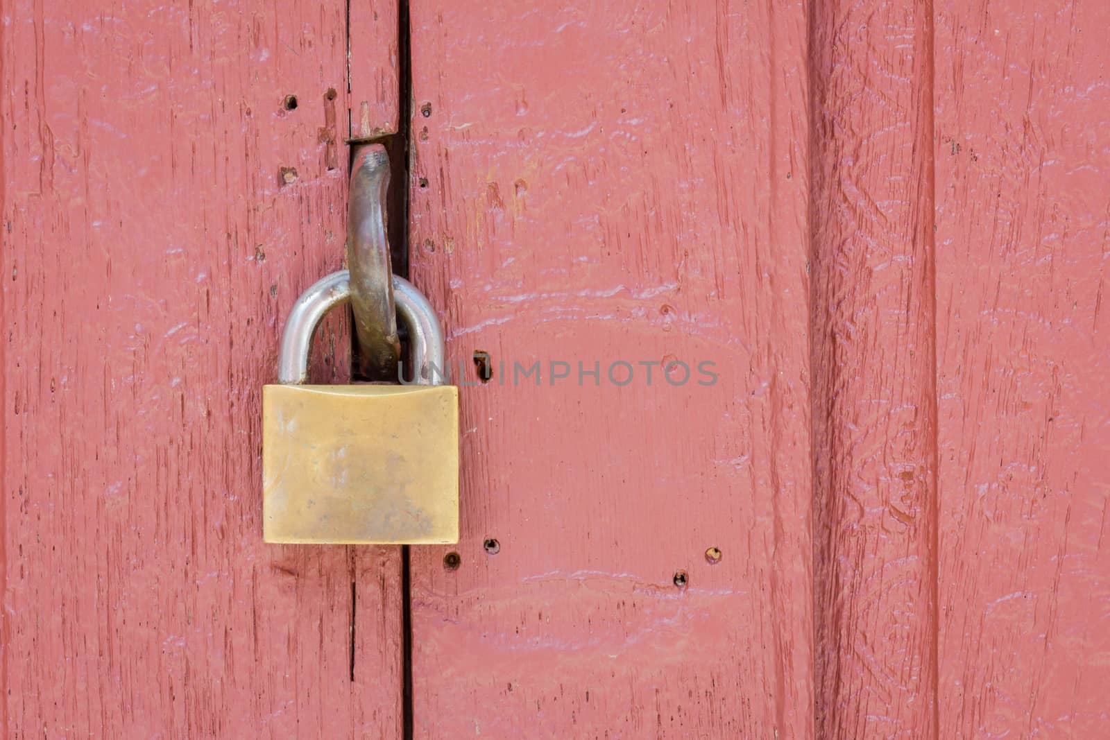 closeup of lock on the middle of pale red wood door, copyspace on the right