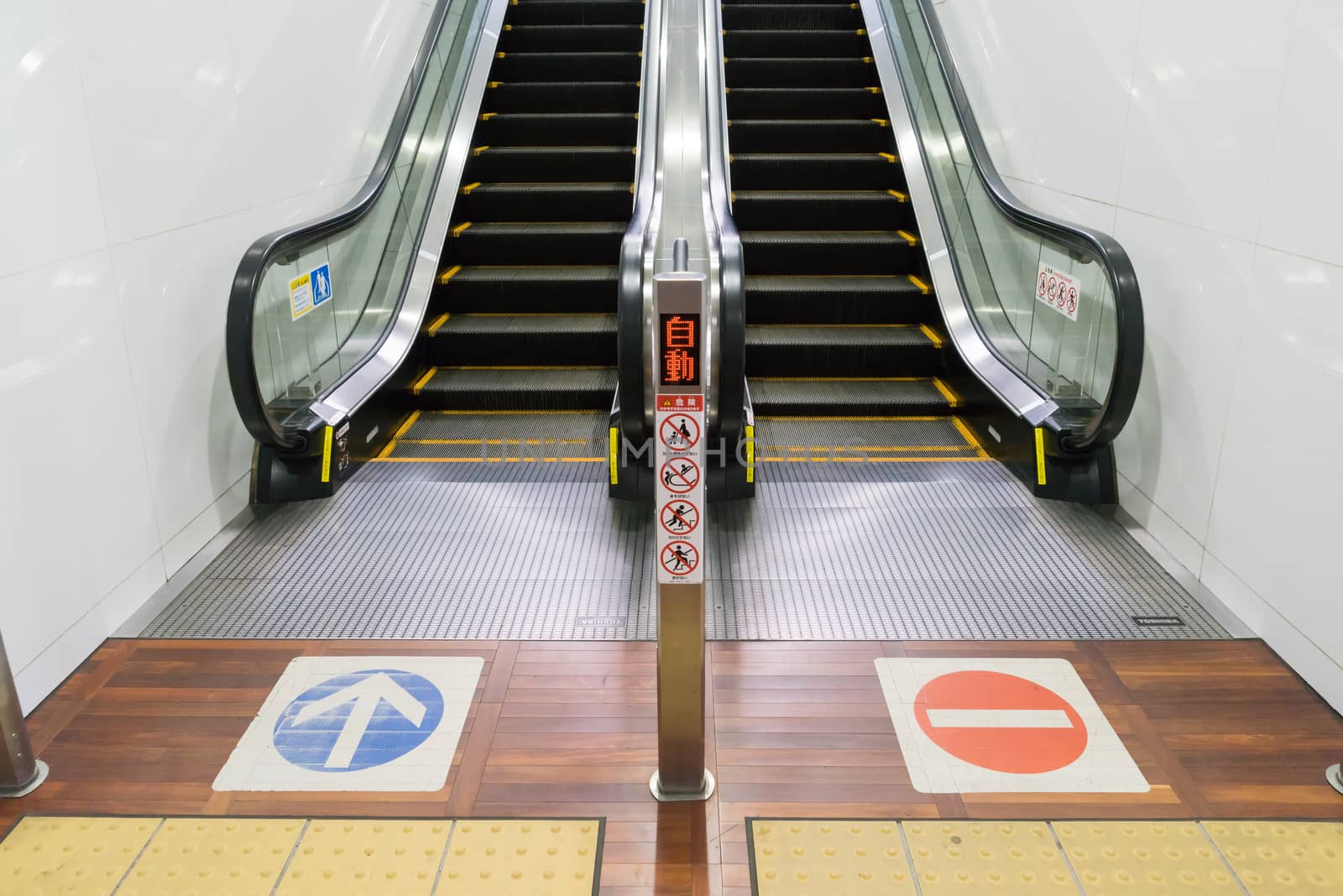 an escalator upstair way and downstair way with sign on the floor