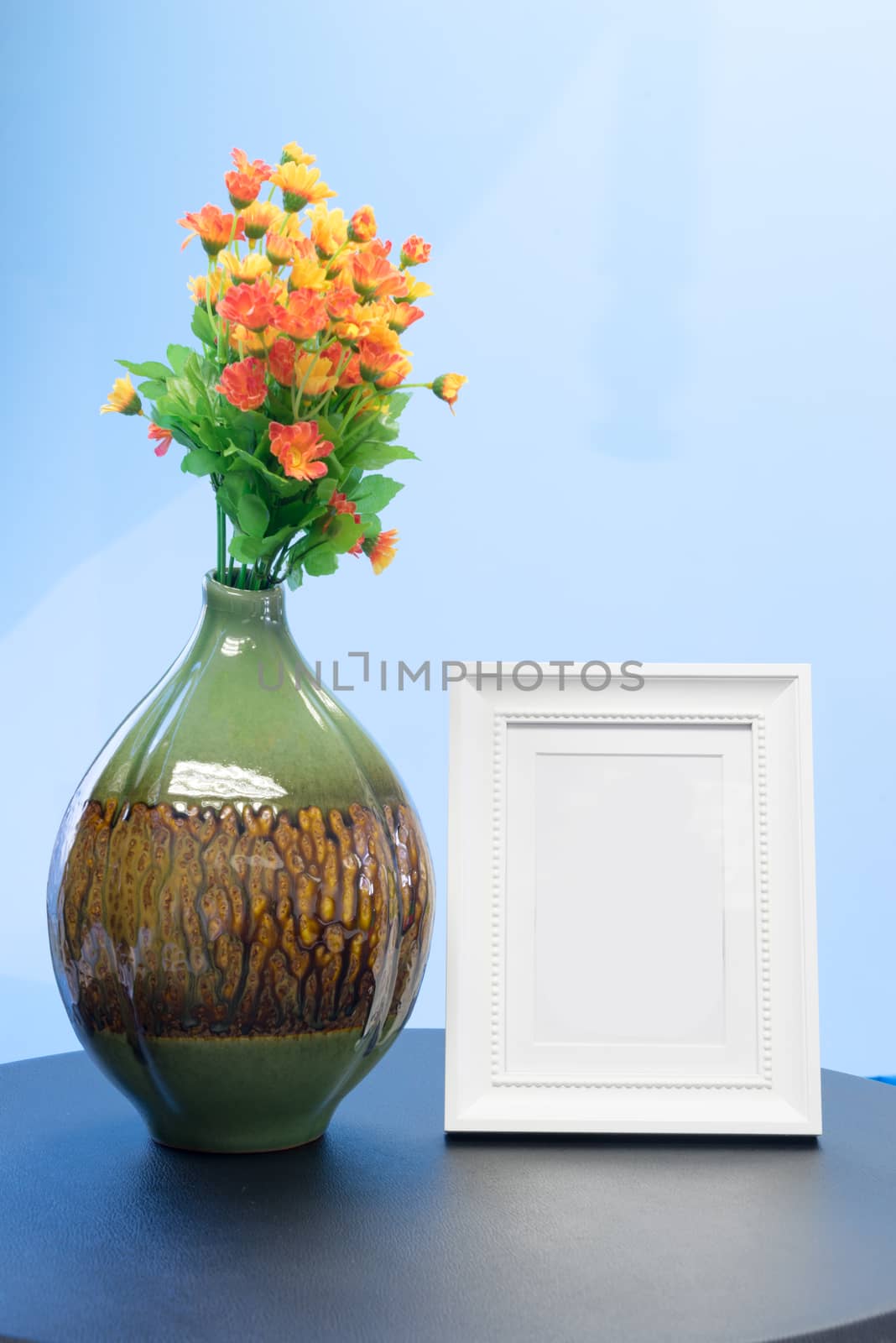 Bouquet of plastic flowers Placed on the desk in the office beside blank photo frame