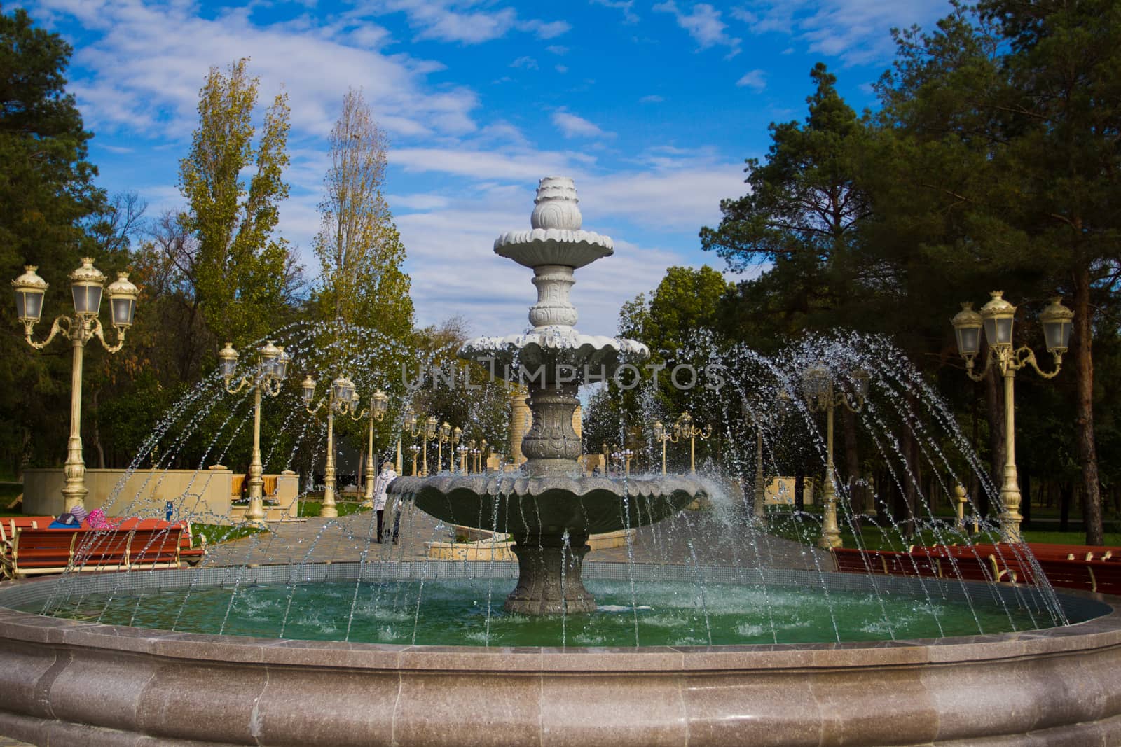 The fountain on the background of blue sky. Spring in city park