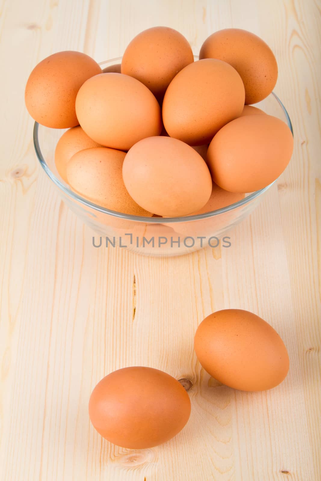 Fresh brown eggs in a bowl on wooden table