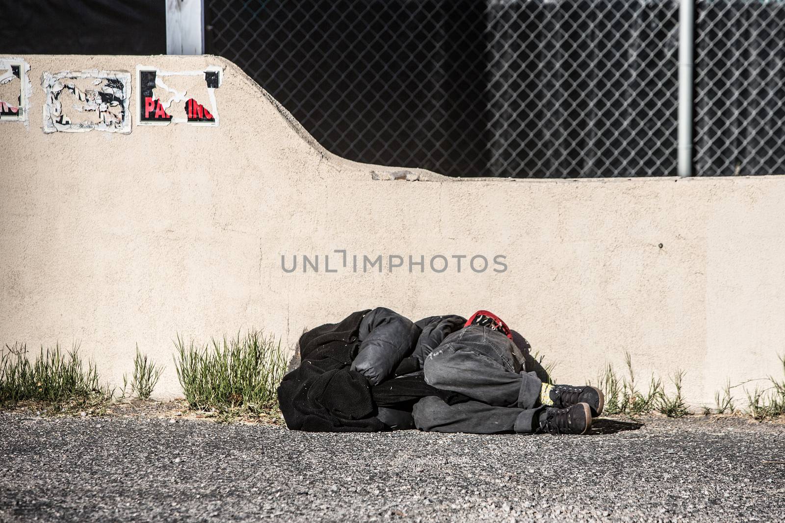 Homeless person sleeping near wall in parking lot