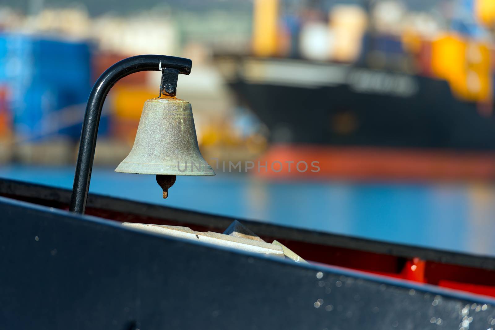 Old bronze bell on a boat, in the background a large merchant ship blurred