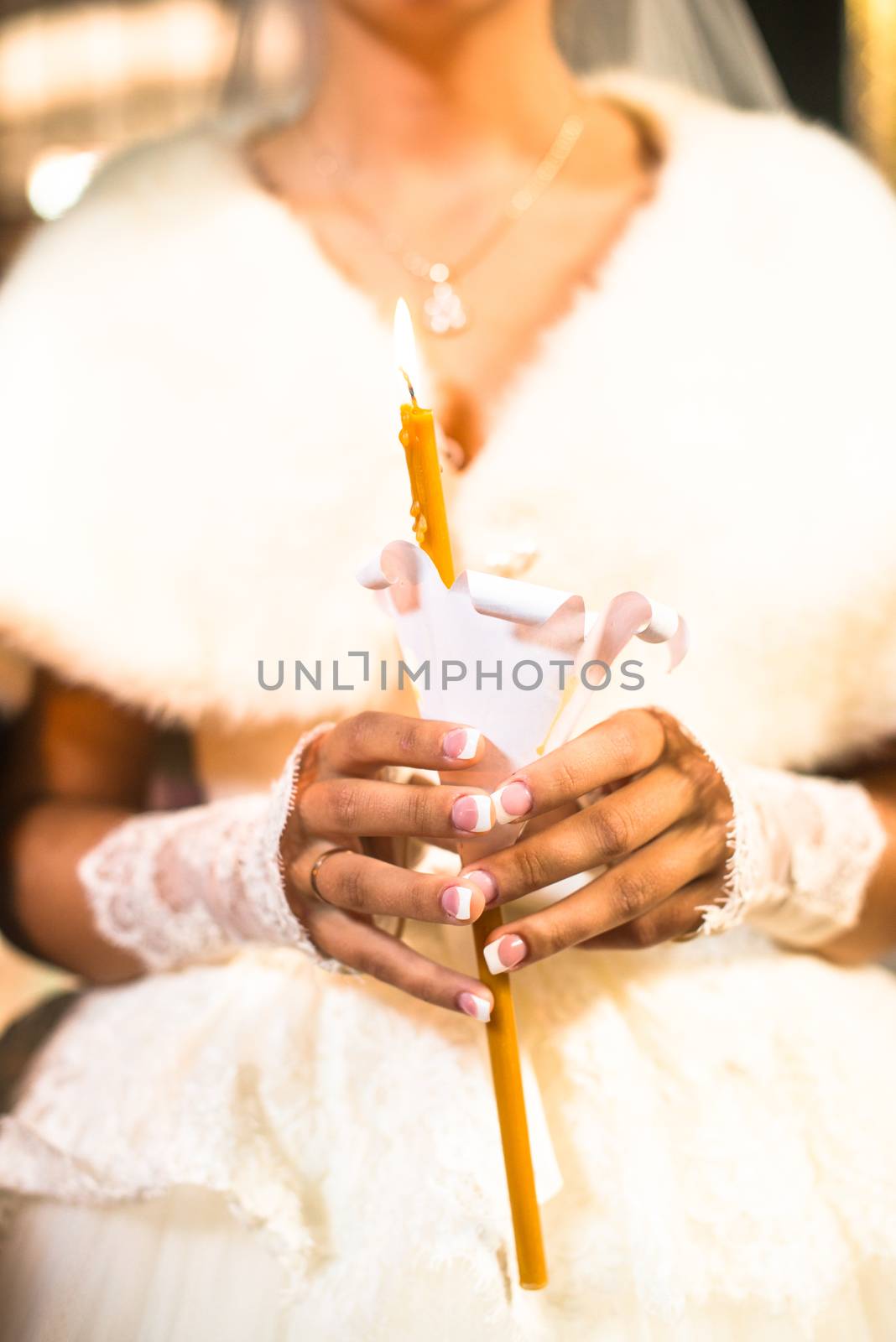 Bride holding the candle during the wedding ceremony in orthodox church. Close up.