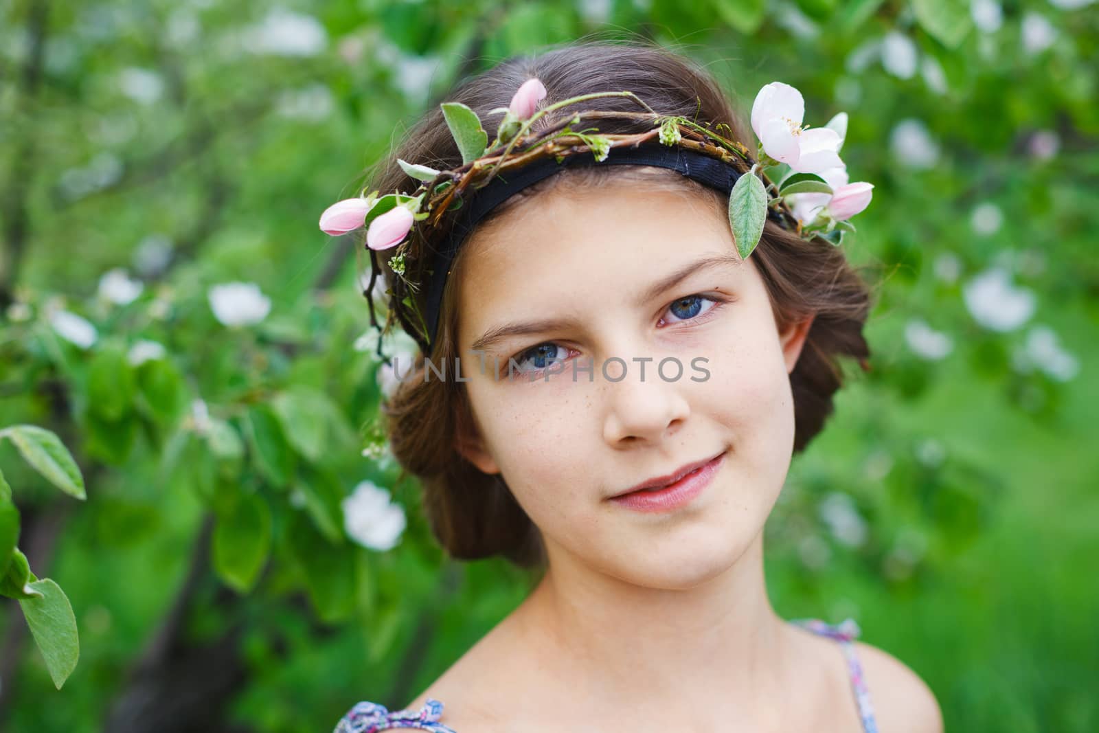 Portrait of adorable girl in blooming apple tree garden on spring day