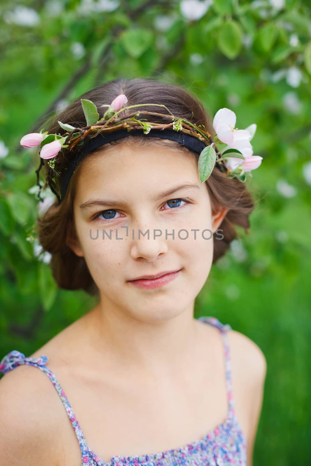 Portrait of adorable girl in blooming apple tree garden on spring day