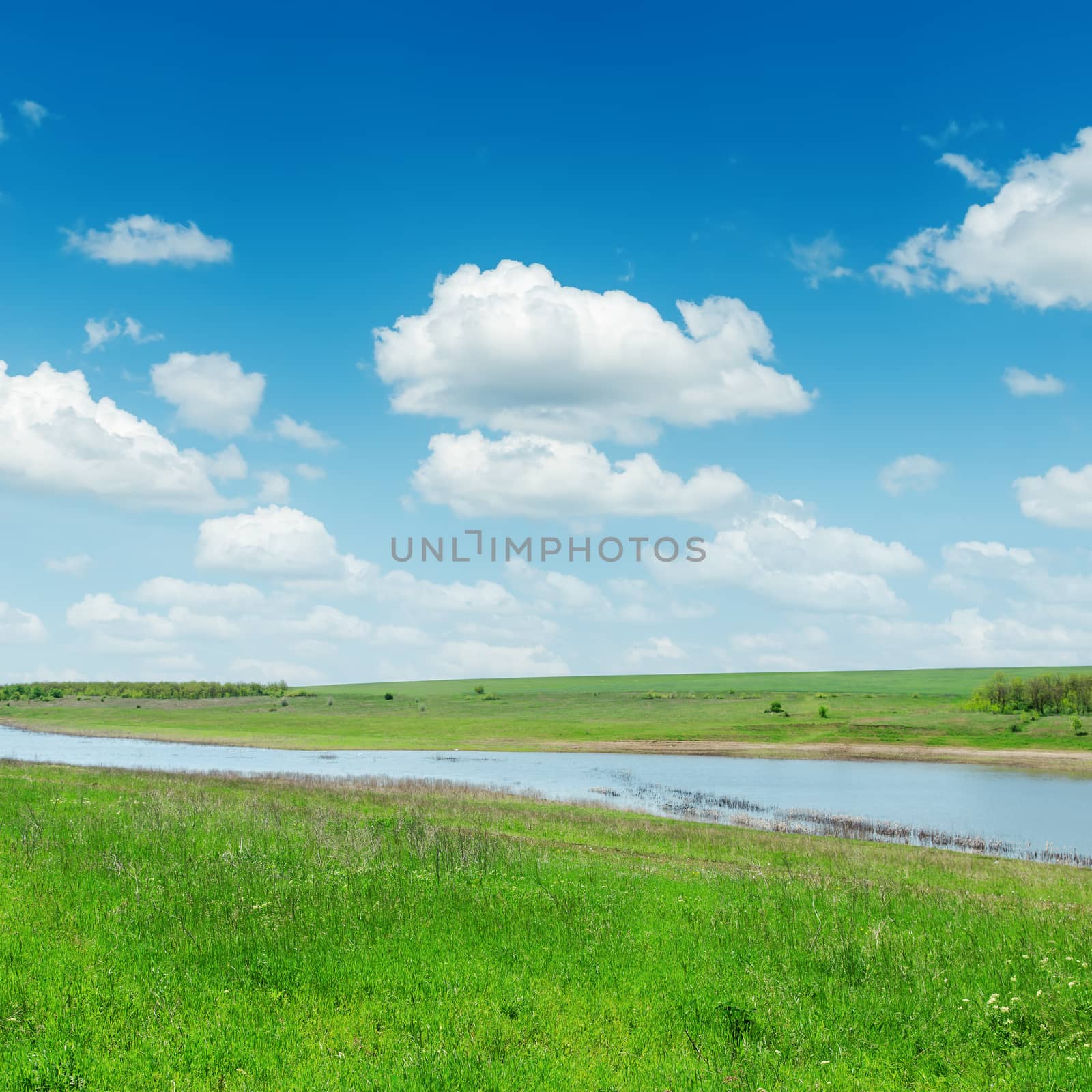 river in green grass under sky with clouds by mycola