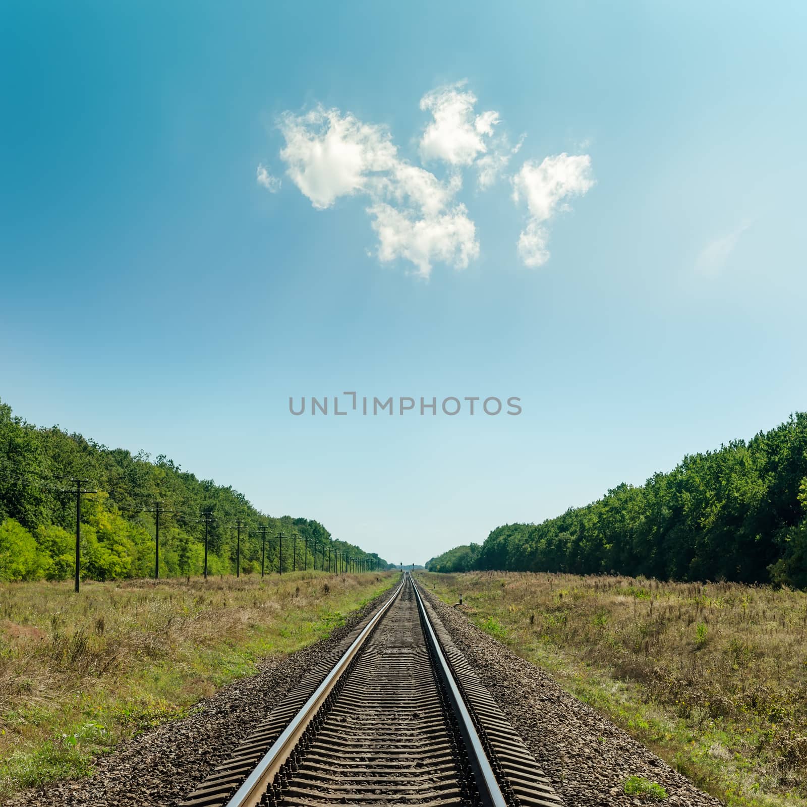 light clouds in blue sky over railroad to horizon
