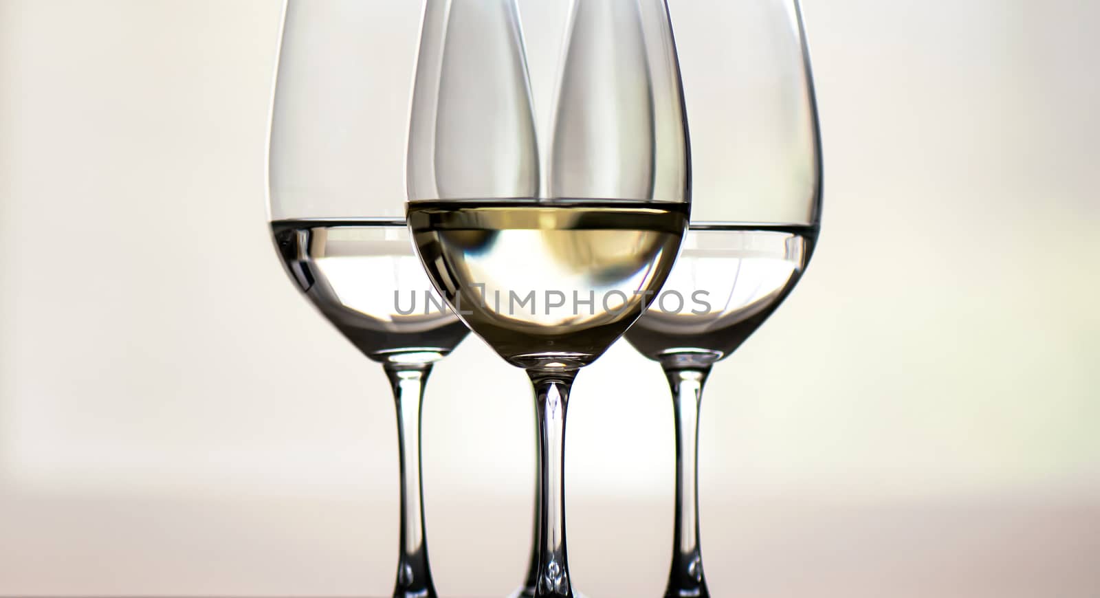 Four glasses of white wine, arranged symmetrically, focus on the middle one