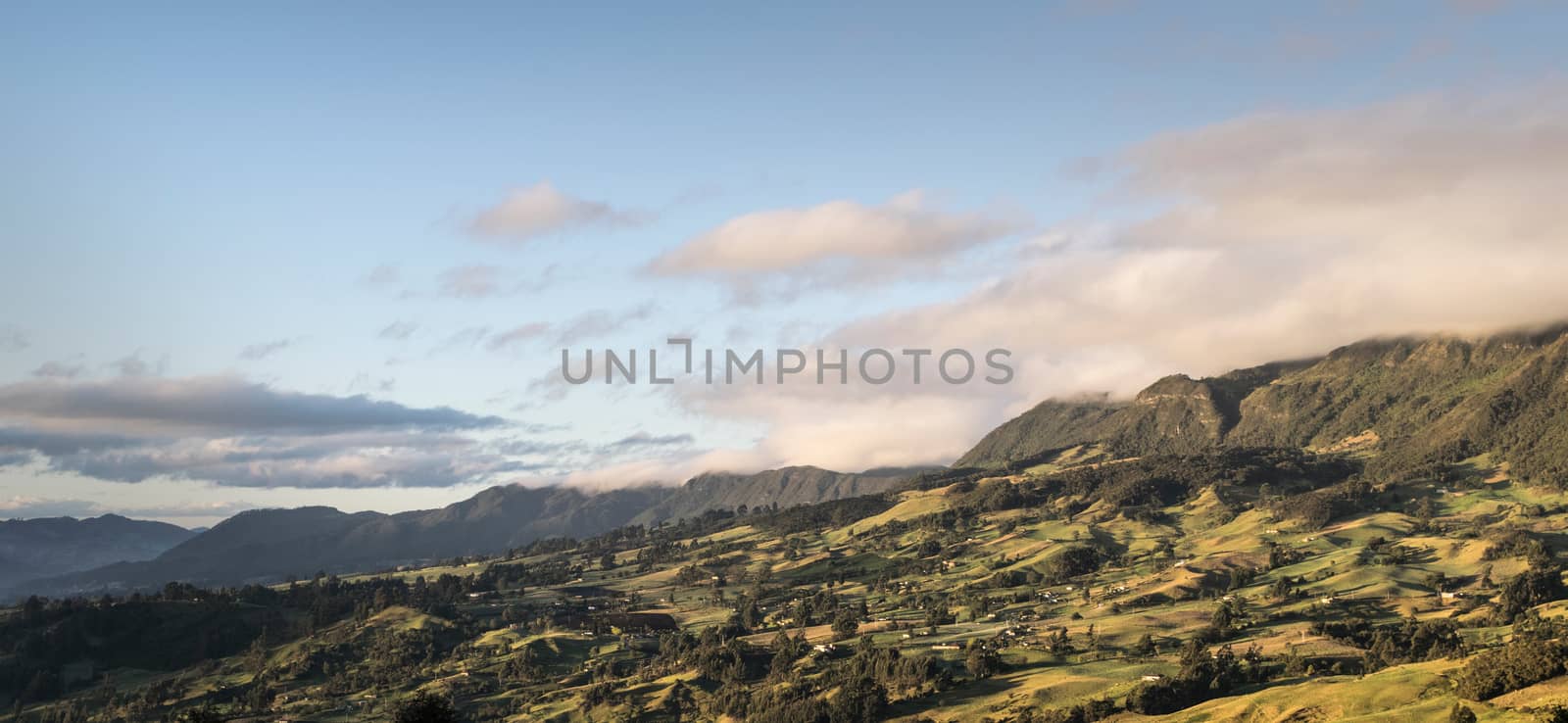 Green valley illuminated by the first rays of sun, accentuating the shadows of the small hills