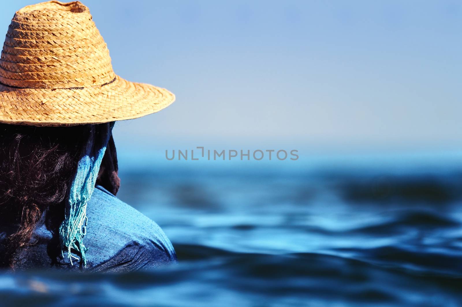 Woman with hat swim in dress in the sea