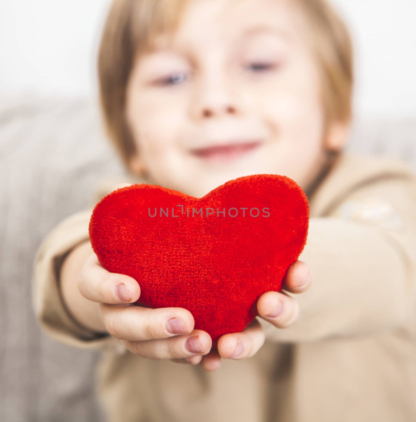 Cute young boy with a red heart in his hands