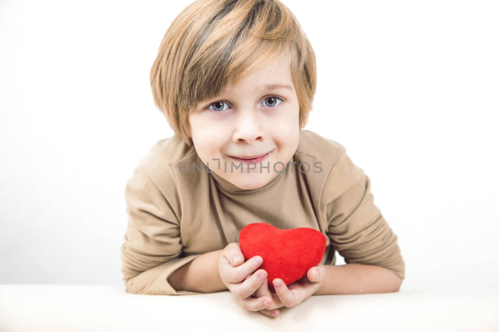 Cute young boy with a red heart in his hands