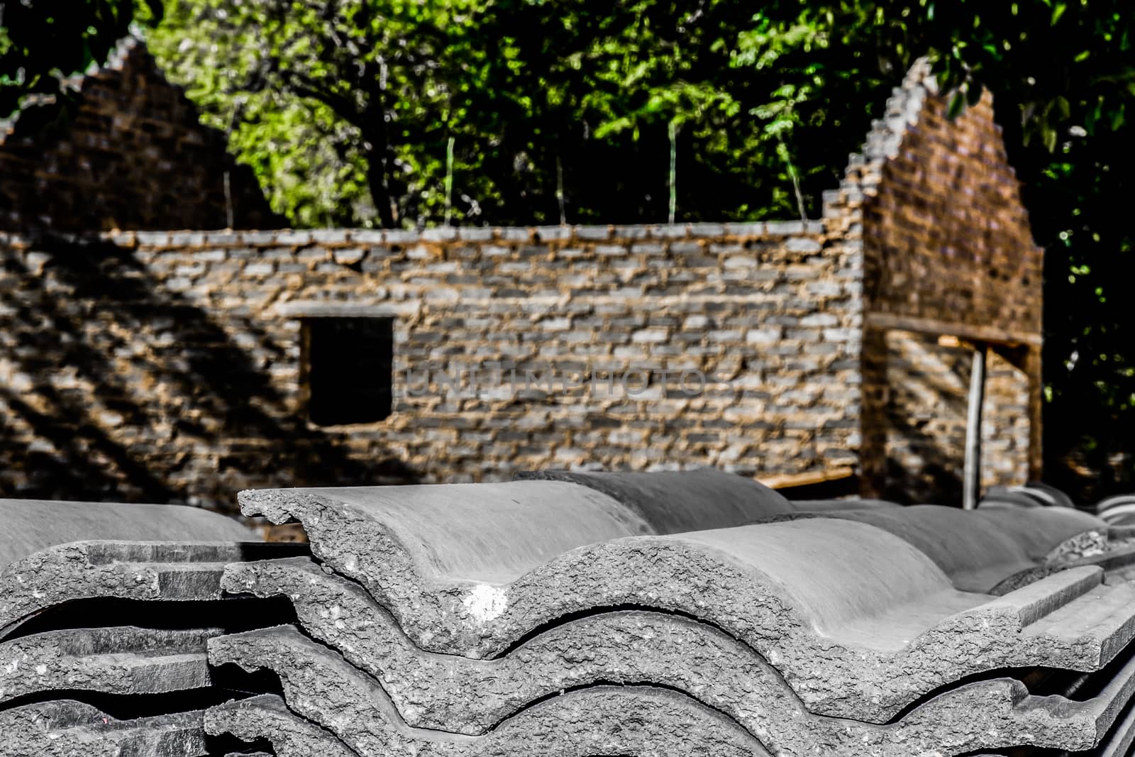 Roof tiles are stacked beside an incomplete house, ready to be placed on the roof of the house.