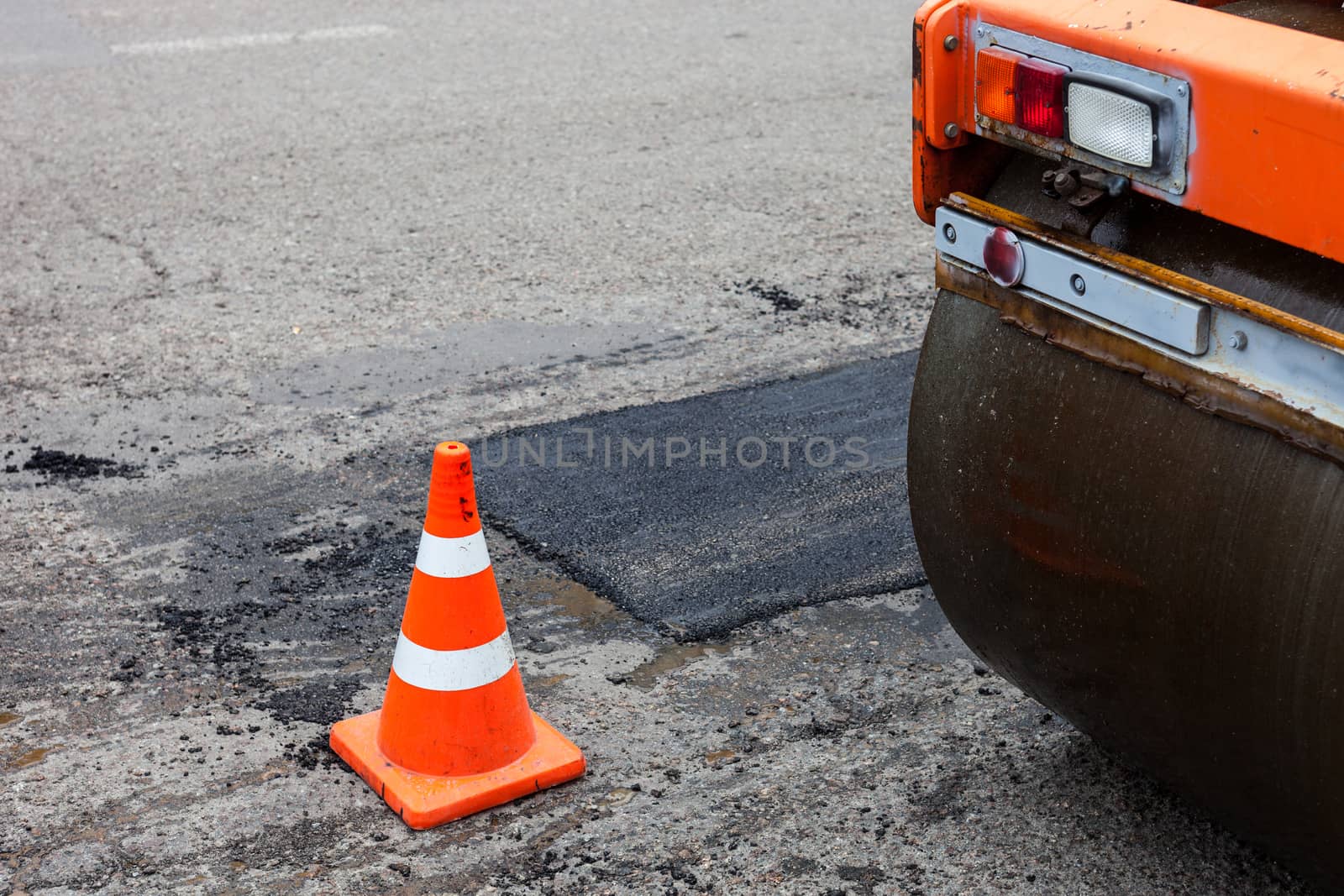 Road roller and traffic cone on the road construction by rootstocks