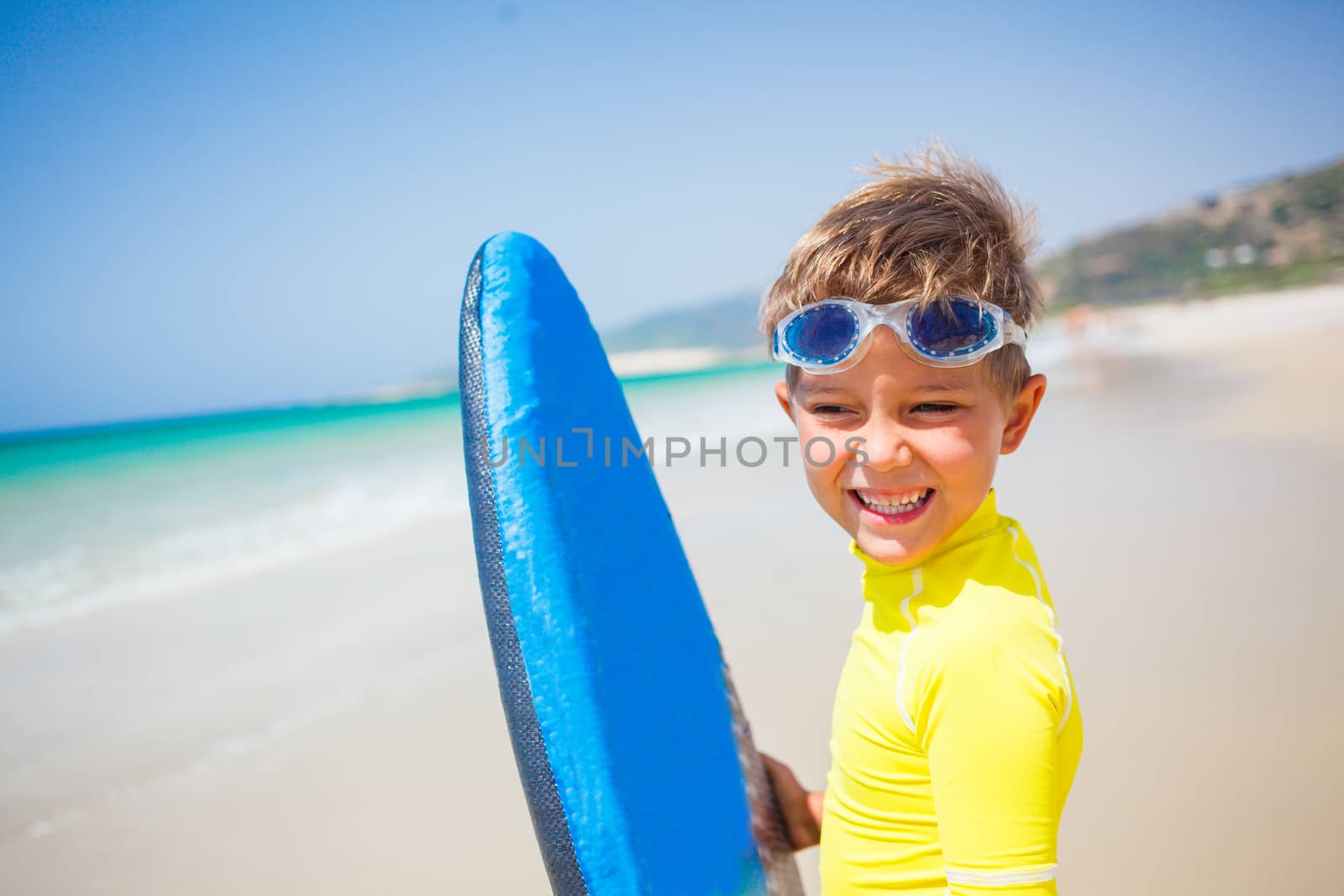 Portrait of little boy in yellow has fun surfing