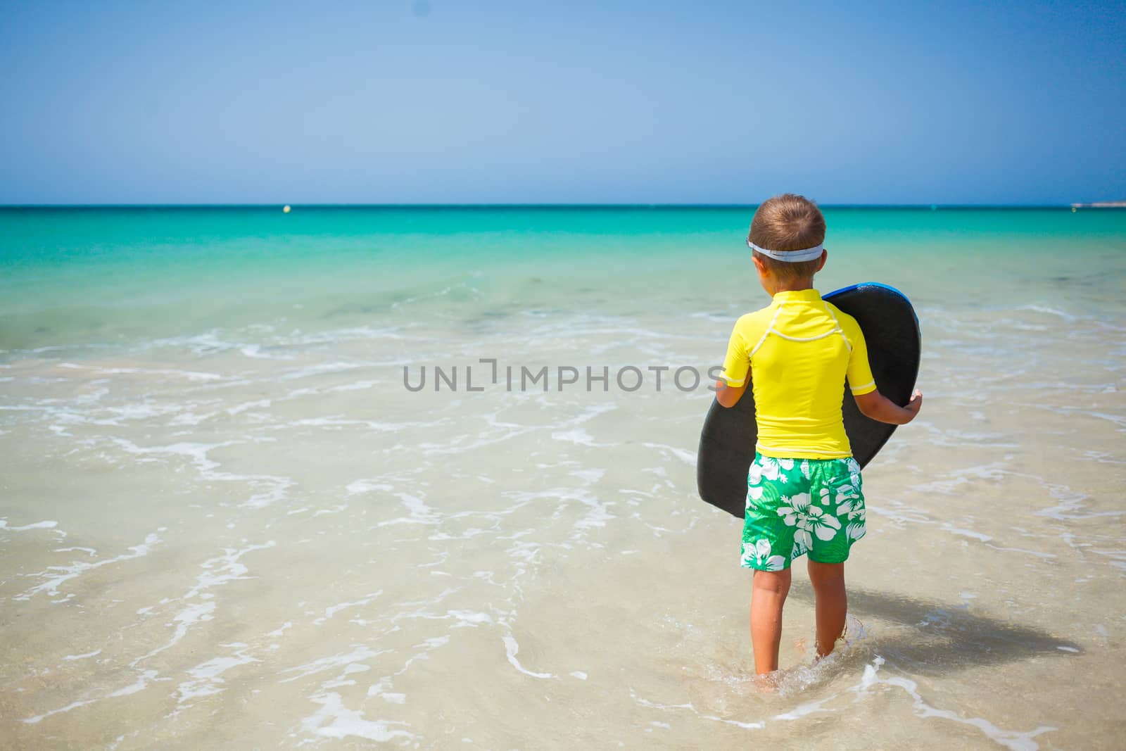 Little boy in yellow has fun surfing