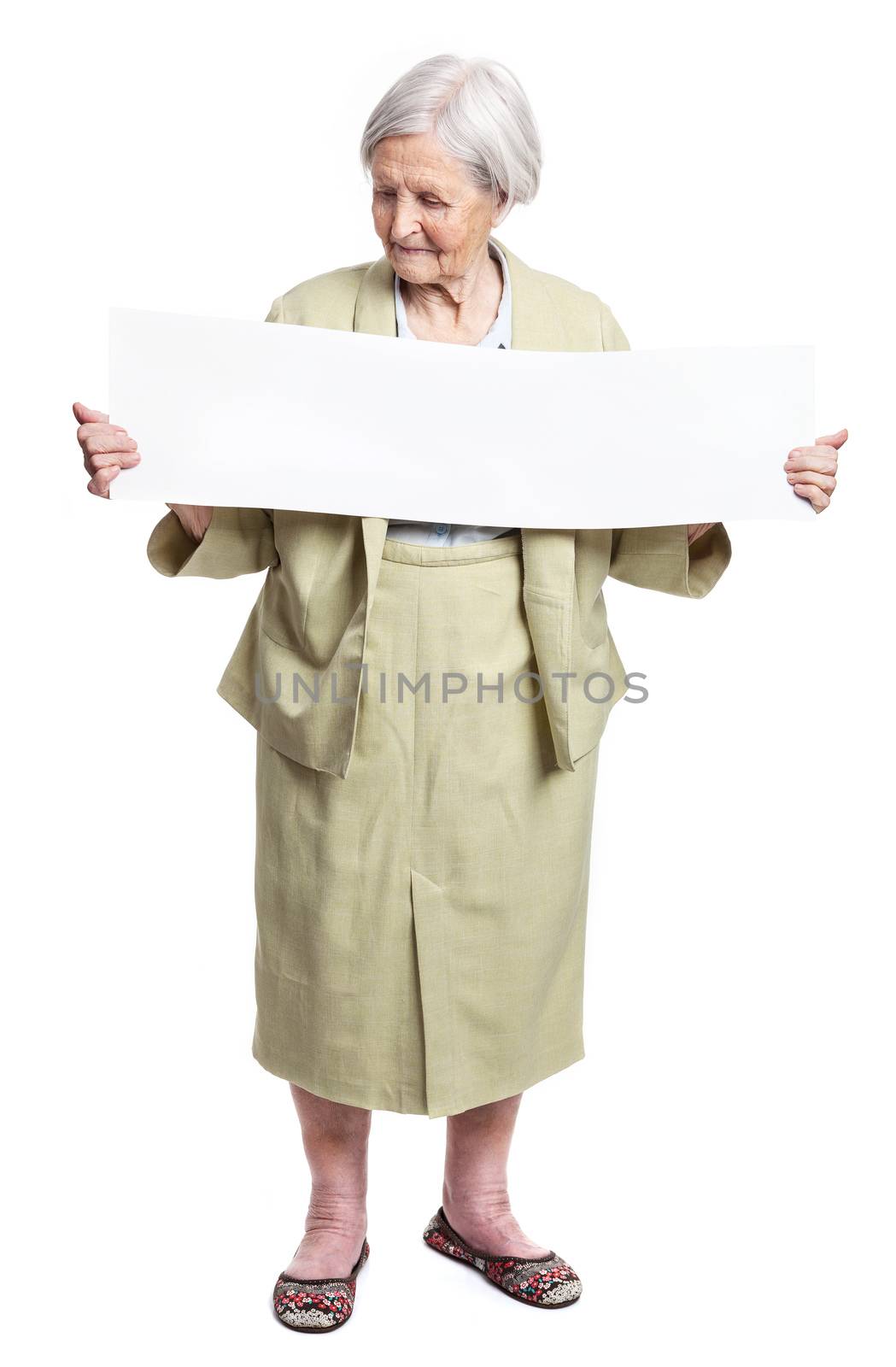 Smiling elderly lady holding blank sheet in hands over white