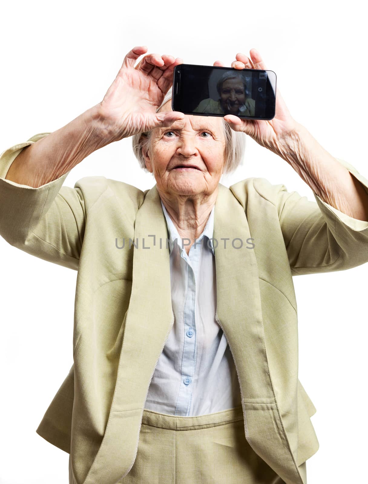 Elderly woman using mobile for taking selfie by photobac