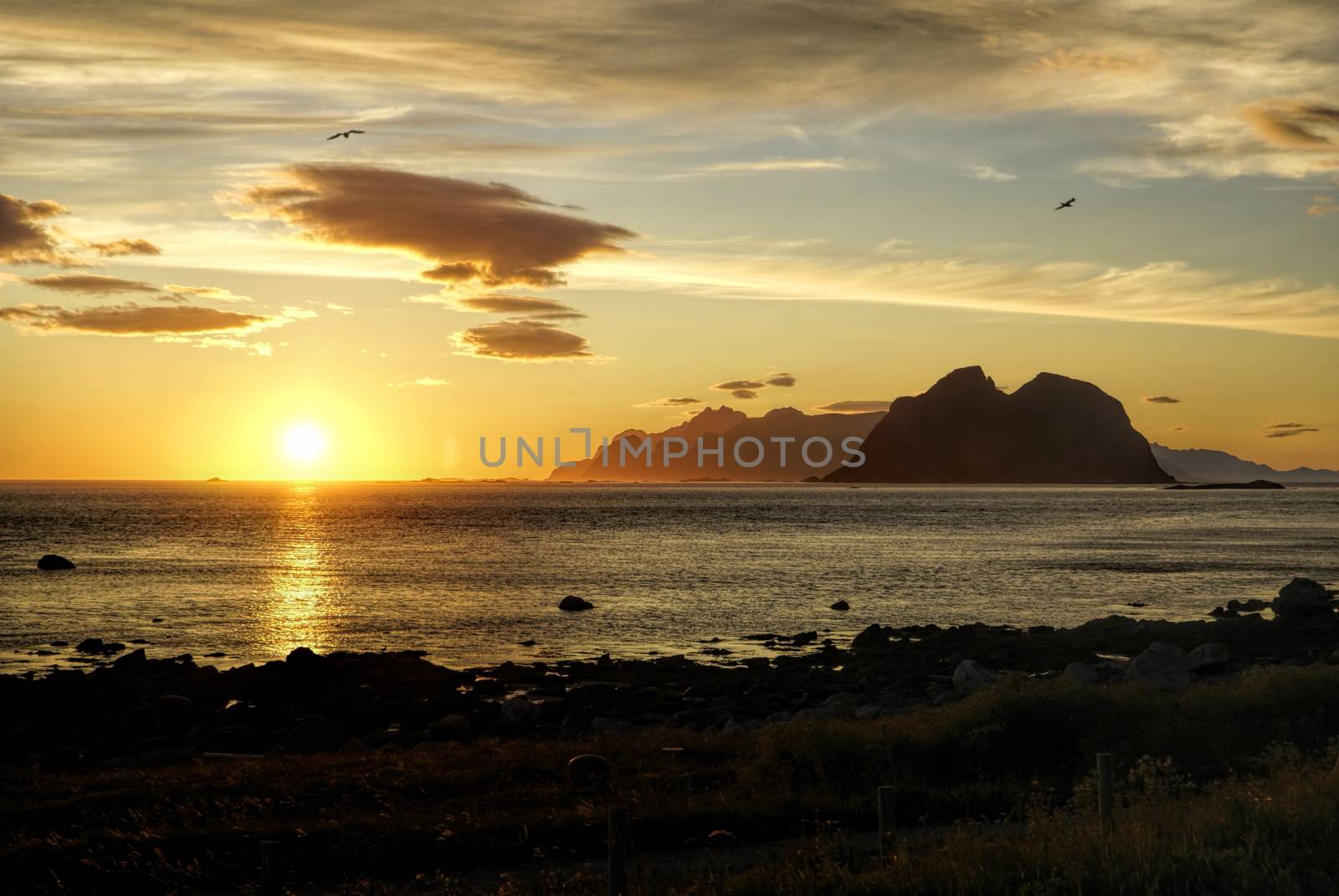 Breathtaking view of sunset over calm ocean and high mountains