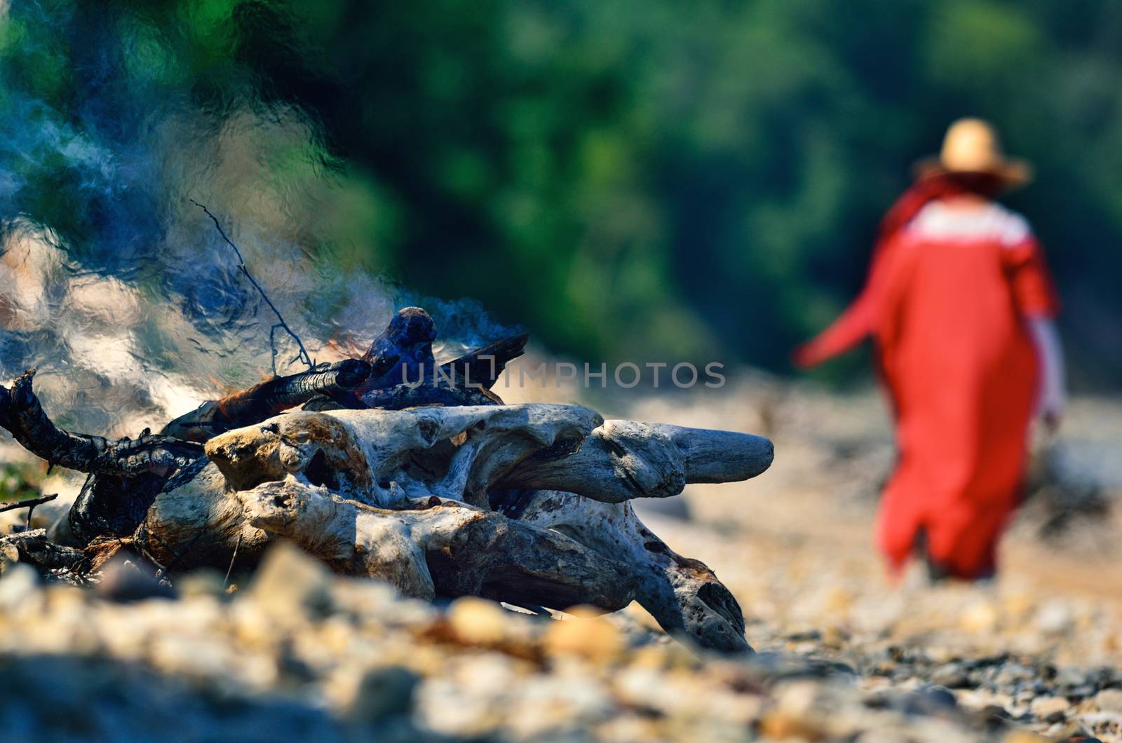 Woman in red dress near the campfire on the coast