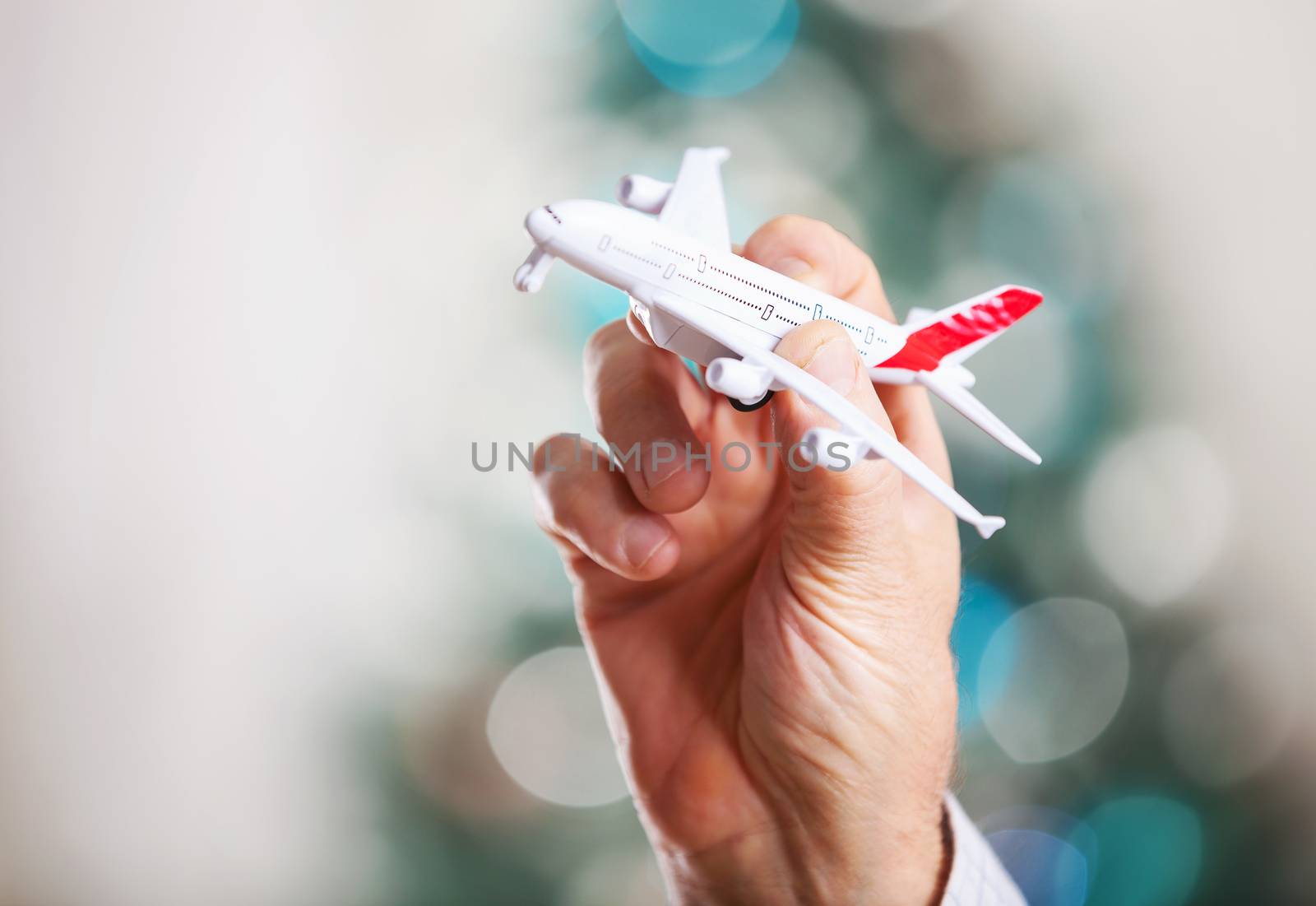 Man hand holding model of airplane by photobac