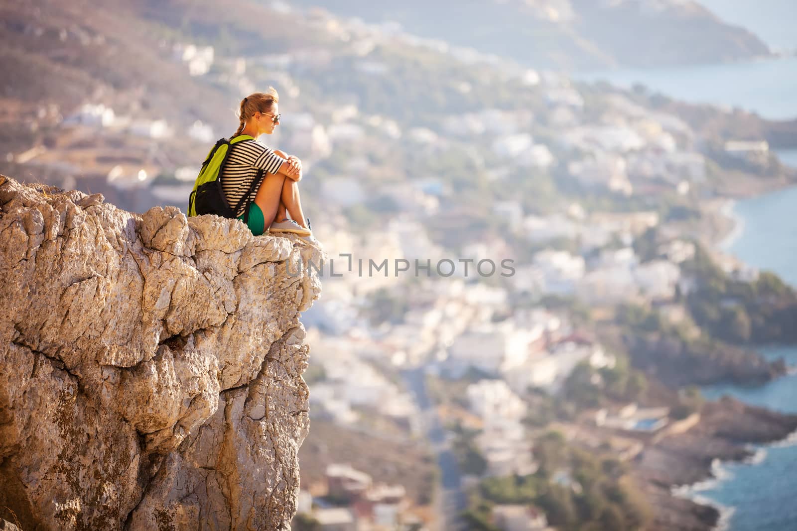 Young woman sitting on rock by photobac